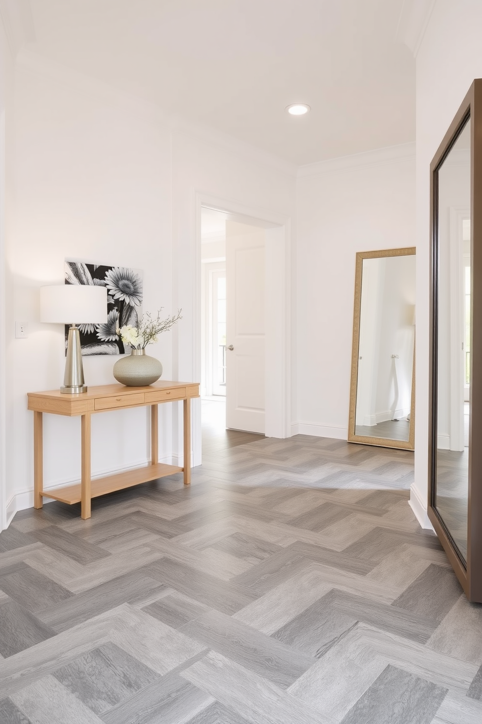 A stylish foyer featuring gray tile flooring with geometric patterns that create a modern and sophisticated look. The walls are painted in a soft white hue, enhancing the brightness of the space and complementing the flooring design. An elegant console table made of light wood stands against one wall, adorned with a minimalist lamp and a decorative bowl. To the side, a large mirror with a sleek frame reflects the foyer's beauty, making the area feel more spacious and inviting.