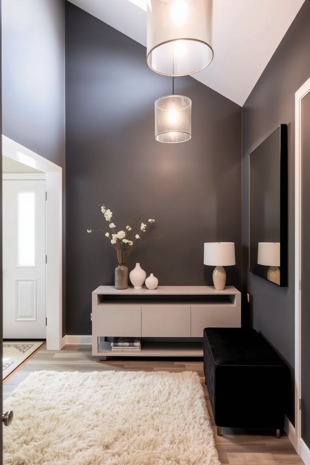 A bold gray accent wall serves as the focal point of the foyer, creating a dramatic entrance. The space features a sleek console table adorned with decorative objects and a large mirror that reflects light throughout the area. Soft lighting fixtures hang from the ceiling, adding warmth to the modern design. A plush area rug in neutral tones lies beneath, complementing the gray hues and enhancing the overall aesthetic.