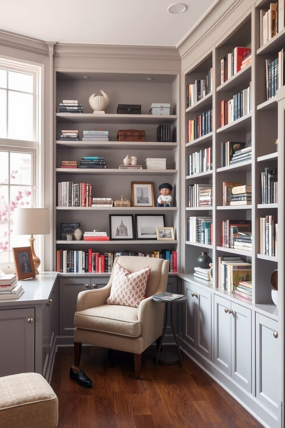 A cozy home library featuring built-in shelves in soft gray tones that stretch from floor to ceiling. The shelves are filled with an array of books, decorative boxes, and personal mementos, creating an inviting atmosphere. A comfortable reading nook is nestled in one corner, adorned with a plush armchair and a small side table. Large windows allow natural light to flood the space, enhancing the serene ambiance of the room.