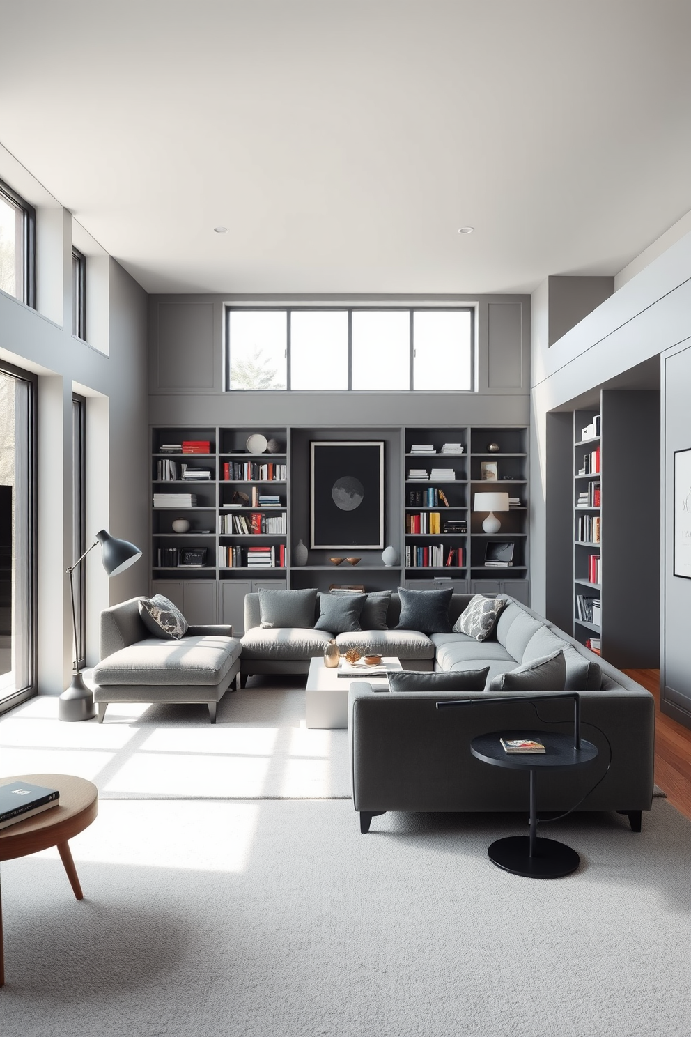 A minimalist gray home library featuring sleek lines and a spacious layout. The walls are painted in a soft gray hue, complemented by built-in shelves filled with books and decorative items. A large, comfortable sectional sofa in a darker gray sits in the center, paired with a simple coffee table. Natural light floods the space through large windows, highlighting a cozy reading nook with a stylish armchair and a floor lamp.