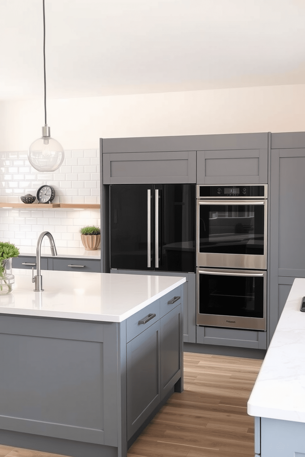 A modern kitchen featuring sleek gray cabinetry with integrated appliances that create a seamless look. The countertops are a light quartz, complementing the cabinetry, while a large island provides additional workspace and seating. The backsplash is a glossy white subway tile that adds brightness to the space. Pendant lights hang above the island, casting a warm glow over the kitchen area.