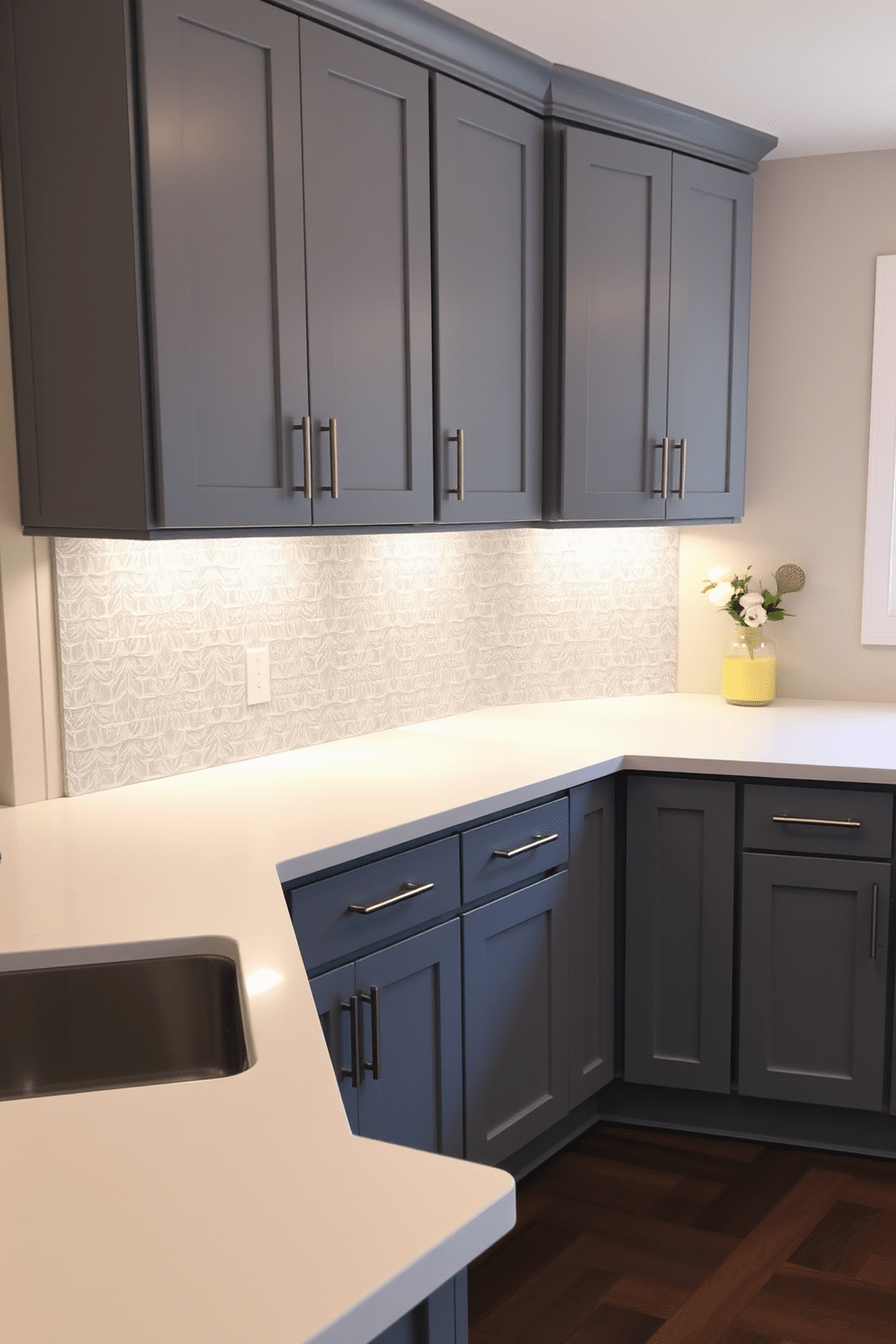 Sleek gray cabinets with under-cabinet lighting create a modern and inviting atmosphere in the kitchen. The countertops are a contrasting white quartz, and a stylish backsplash in a geometric pattern adds visual interest.