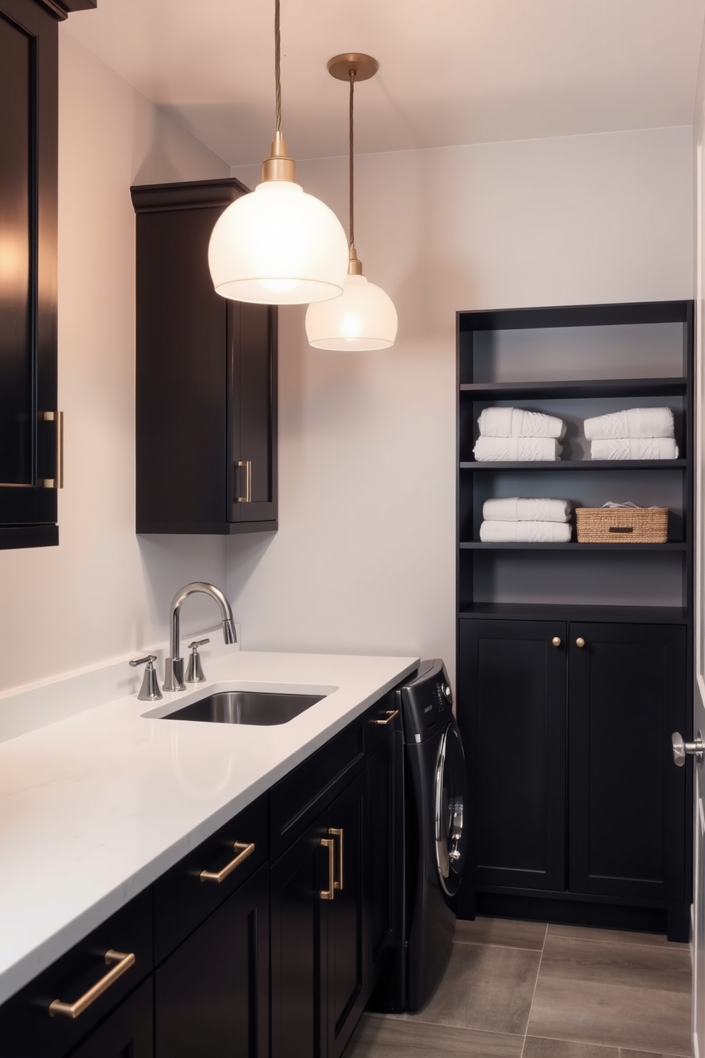 Chic pendant lights hang gracefully from the ceiling, casting a warm glow over the sleek gray laundry room. The walls are painted in a soft gray tone, complemented by dark cabinetry that provides ample storage space. A stylish countertop made of white quartz offers a practical workspace for laundry tasks, while a vintage-inspired sink adds character to the room. To enhance functionality, a set of open shelves displays neatly folded towels and laundry essentials, creating an organized yet inviting atmosphere.