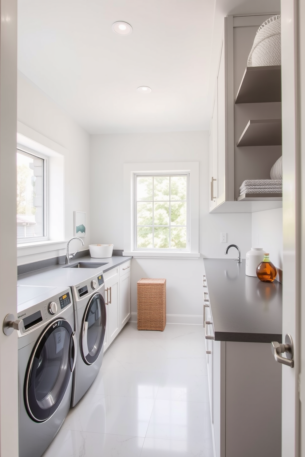 A modern laundry room featuring sleek gray countertops that complement the stainless steel appliances. The walls are painted in a soft white, creating a bright and airy atmosphere. A large window allows natural light to flood the space, enhancing the clean lines and minimalistic design. Stylish storage solutions are integrated into the cabinetry, providing both functionality and elegance.