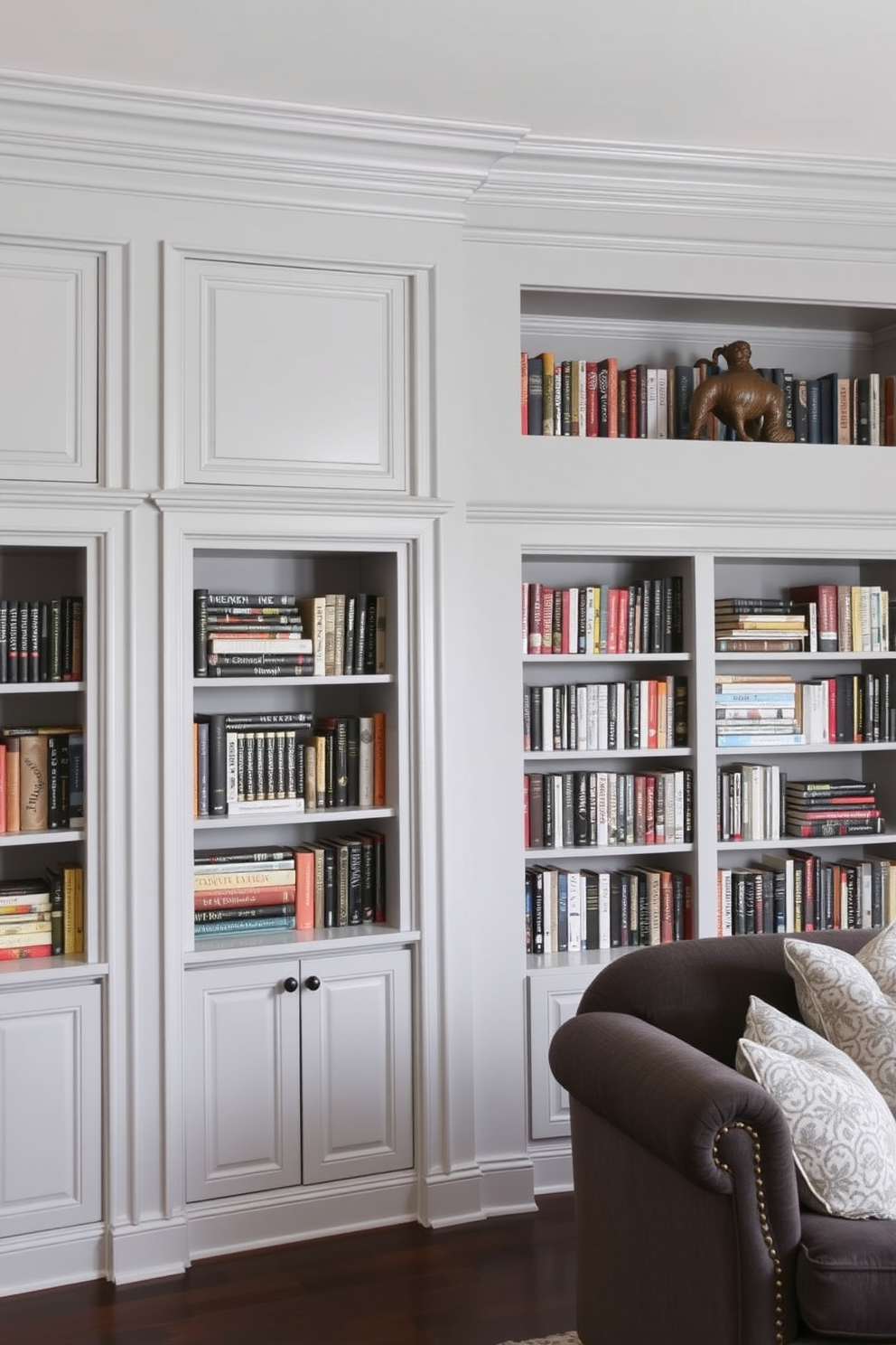 A stylish gray living room featuring built-in shelves filled with an array of books. The shelves are framed by elegant moldings, creating a seamless integration with the room's soft gray walls.