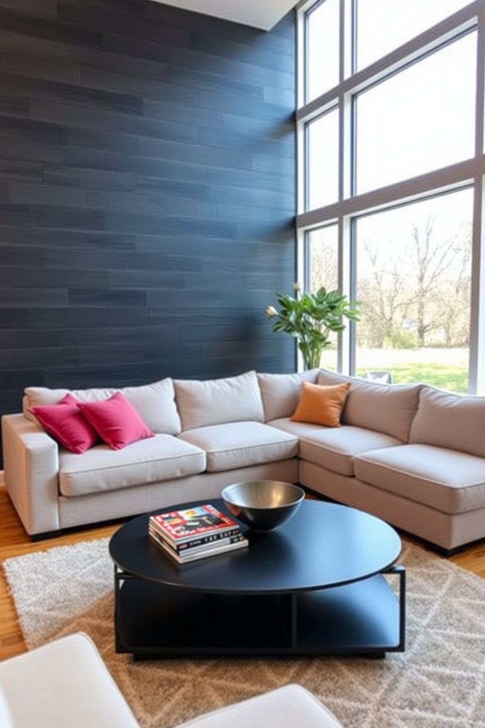 Accent wall with dark gray shiplap. The living room features a plush sectional sofa in a light fabric, complemented by vibrant throw pillows. A sleek coffee table sits in front of the sofa, adorned with a stack of art books and a decorative bowl. Floor-to-ceiling windows allow natural light to flood the space, highlighting the warm wooden flooring.