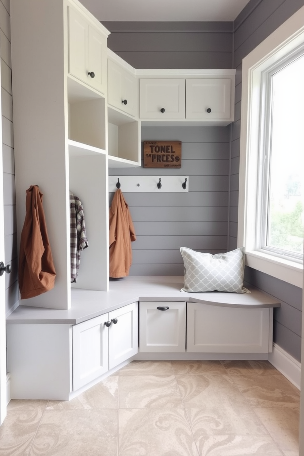 A stylish mudroom with gray shiplap walls creates a warm and inviting atmosphere. Built-in storage solutions are seamlessly integrated, featuring cubbies and hooks for organization. The flooring is a durable tile that complements the gray tones. Natural light floods the space through a large window, enhancing the overall brightness and appeal.