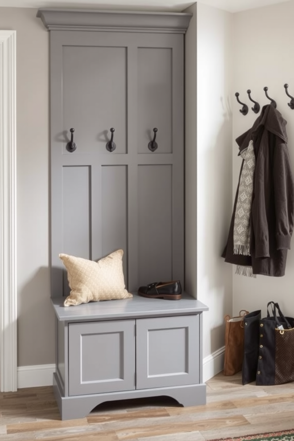 A gray built-in bench with ample shoe storage sits against the wall, providing a functional yet stylish entryway solution. The space is enhanced by soft lighting and decorative hooks for coats, creating an inviting and organized mudroom atmosphere.