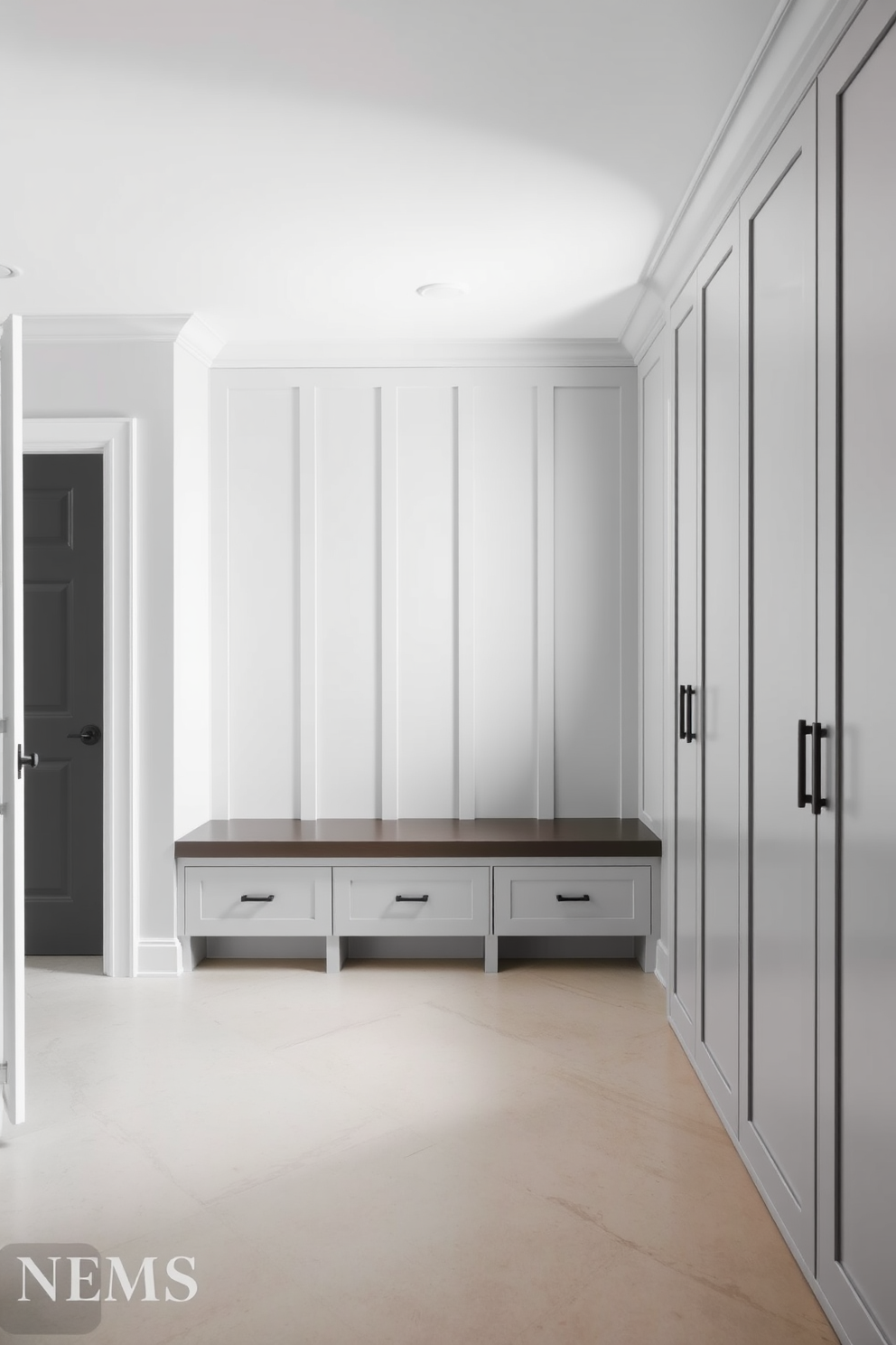 A minimalist gray mudroom featuring clean lines and a spacious layout. The walls are painted in a soft gray hue, complemented by sleek built-in storage units and a simple bench for seating.