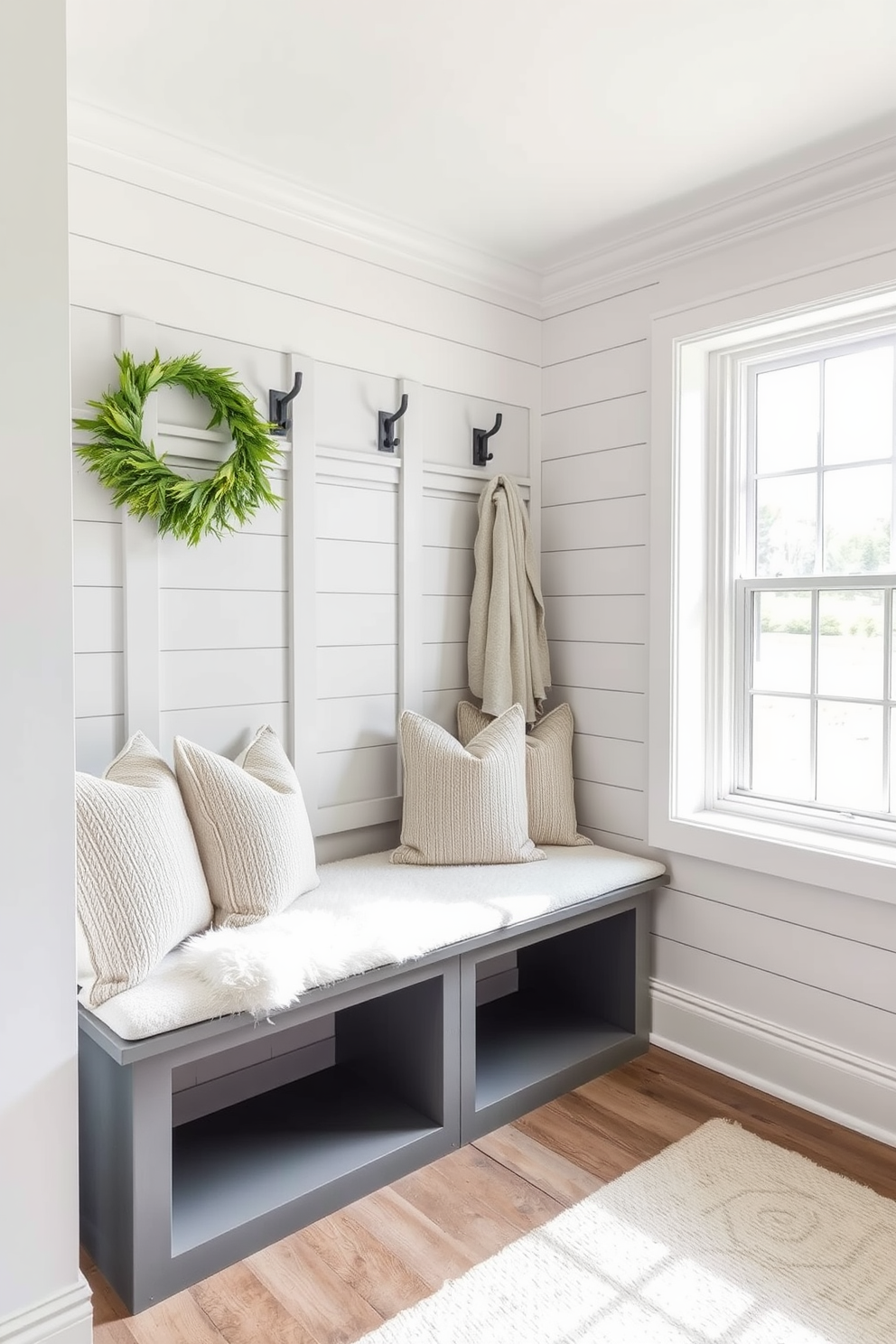 Cozy gray bench with plush cushions in a stylish mudroom. The walls are adorned with shiplap, and natural light streams in through a large window, illuminating the space.