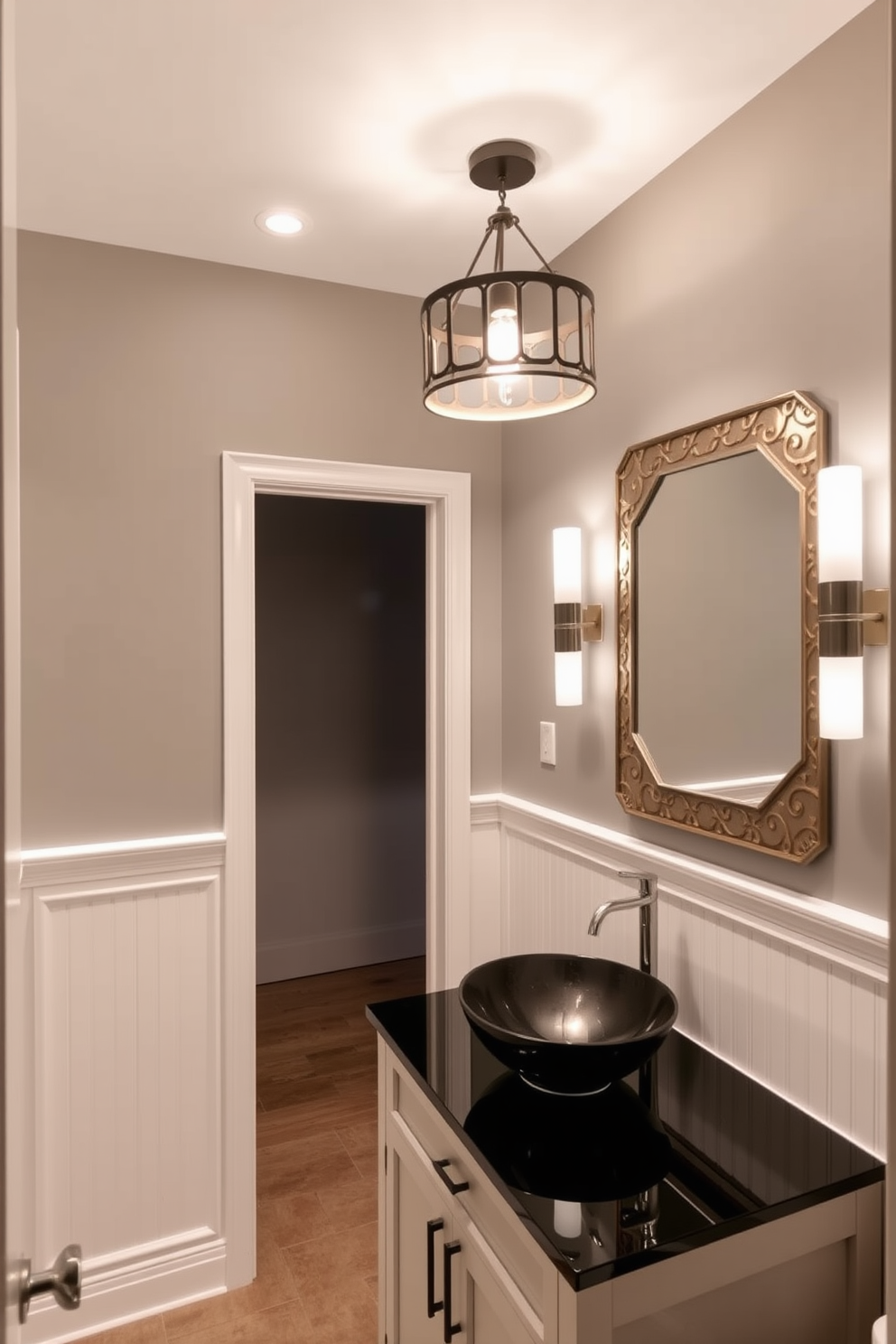 A cozy gray powder room features layered lighting that creates a warm and inviting atmosphere. Soft recessed lights illuminate the space while a stylish pendant light hangs above the sink, providing a focal point. The walls are painted in a soft gray hue, complemented by white wainscoting that adds depth. A sleek vanity with a polished black countertop holds a modern vessel sink, and a decorative mirror enhances the room's elegance.