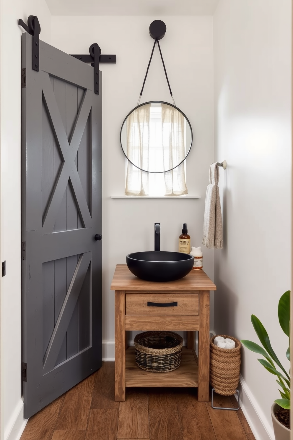 A rustic gray barn door adds character to a chic powder room. The walls are painted in a soft white, complemented by a distressed wooden vanity with a sleek black sink. Natural light filters through a small window adorned with sheer linen curtains. A round mirror with a black metal frame hangs above the vanity, reflecting the warm tones of the space. The floor features reclaimed wood planks, enhancing the rustic charm. Accessories include a woven basket for towels and a potted plant in the corner for a touch of greenery.