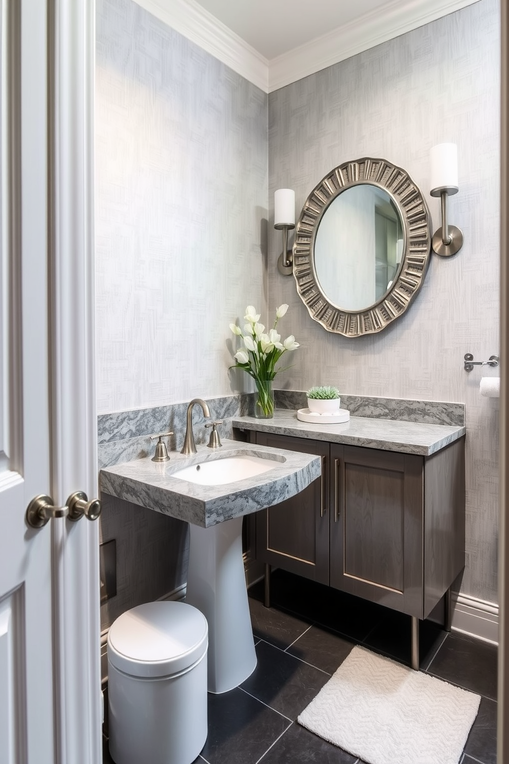 Textured gray stone countertops create an elegant focal point in a chic powder room. The walls are adorned with soft gray wallpaper, and the floor features sleek dark tiles for a modern touch. A stylish pedestal sink complements the countertops, enhancing the room's sophistication. Accents of brushed nickel in the fixtures and a decorative mirror add a refined finishing touch.