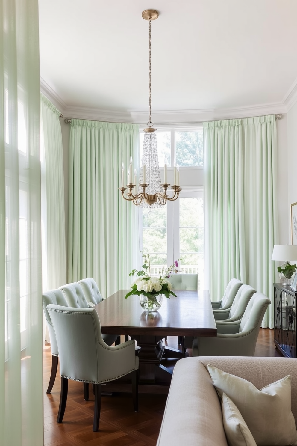 Soft mint green curtains drape elegantly from the ceiling, allowing natural light to filter in and create an airy atmosphere. The dining room features a large wooden table surrounded by upholstered chairs in a complementary shade, enhancing the inviting ambiance. A statement chandelier hangs above the table, casting a warm glow over the space. The walls are adorned with subtle botanical prints, adding a touch of nature to the overall design.