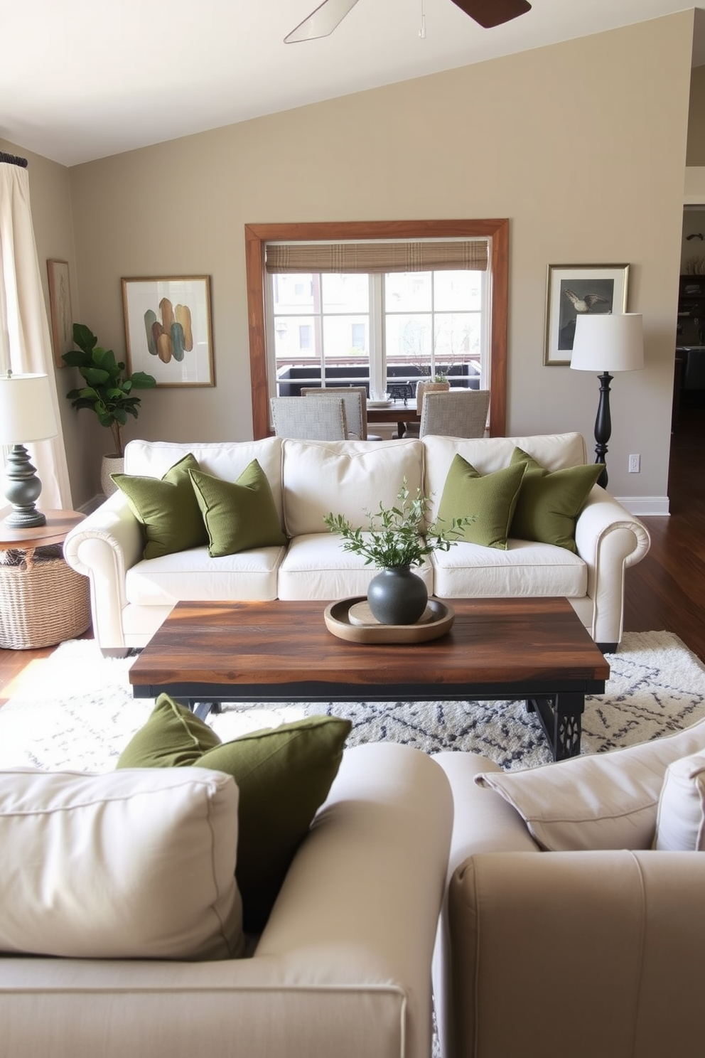 A cozy family room featuring a neutral-colored couch adorned with olive green throw pillows. The space is filled with natural light, highlighting a soft area rug beneath a rustic coffee table surrounded by comfortable seating.