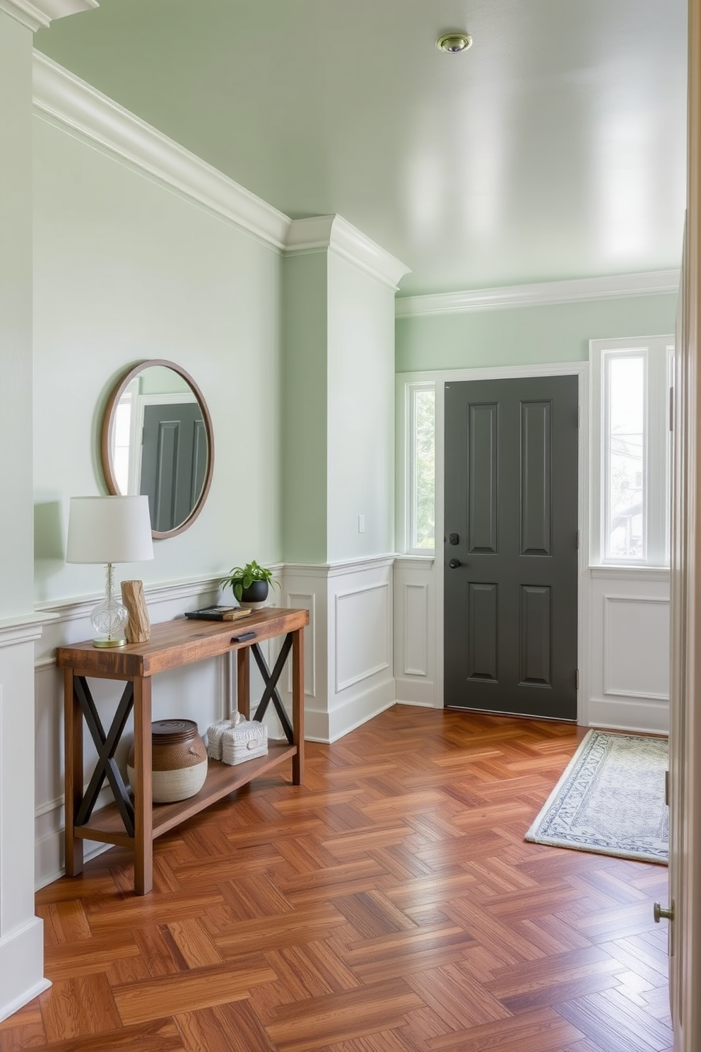 A serene foyer featuring soft green paint on the ceiling creates a calming atmosphere. The walls are adorned with elegant wainscoting, and a large round mirror reflects natural light from the nearby window. A stylish console table made of reclaimed wood sits against one wall, topped with decorative items and a small potted plant. The floor is laid with herringbone-patterned hardwood, adding warmth and texture to the space.