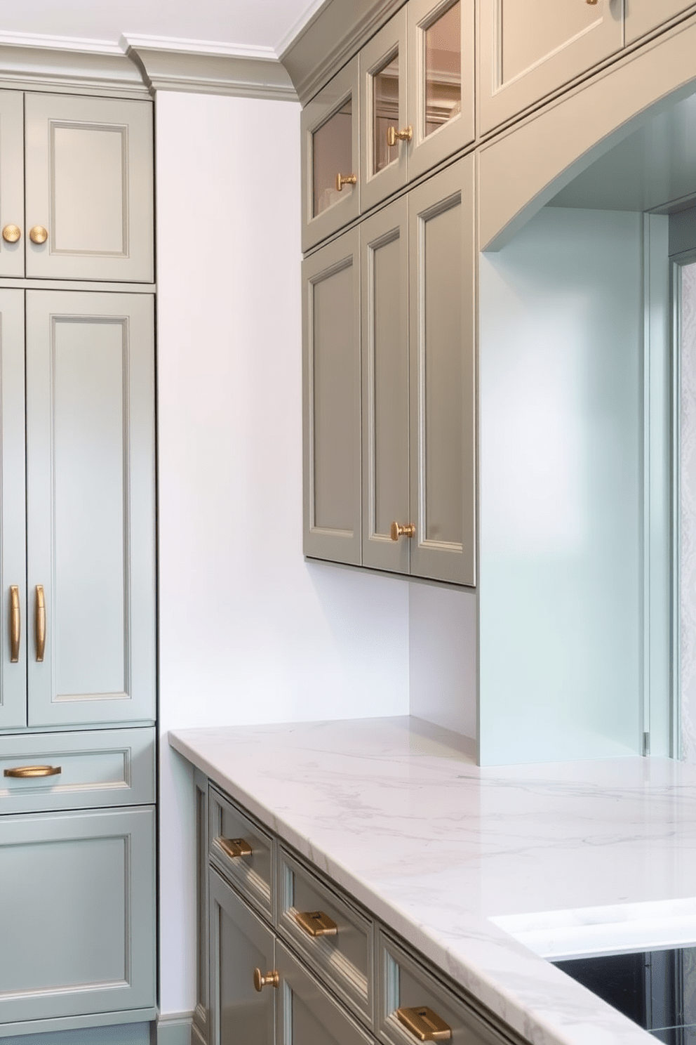 A serene kitchen space featuring soft green cabinets complemented by elegant marble countertops. The cabinetry is adorned with brass handles, and the backsplash showcases a delicate white tile pattern.