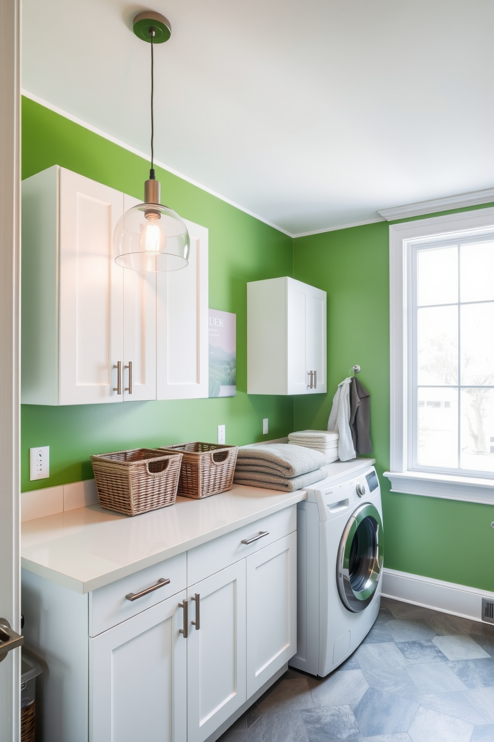 A modern laundry room featuring vibrant green walls that create a fresh and inviting atmosphere. Stylish pendant lighting hangs from the ceiling, illuminating the space and highlighting the sleek white cabinetry. The room includes a spacious countertop for folding clothes, adorned with decorative storage baskets. A large window allows natural light to flood in, enhancing the overall brightness and charm of the laundry area.