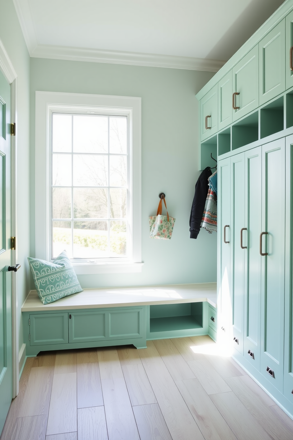 A stylish mudroom featuring mint green lockers provides ample storage space while adding a pop of color. The lockers are arranged along one wall, with hooks above for jackets and bags, and a bench below for comfortable seating. The flooring is a light wood that complements the mint green, creating a fresh and inviting atmosphere. Natural light floods the space through a large window, enhancing the overall cheerful vibe of the mudroom.