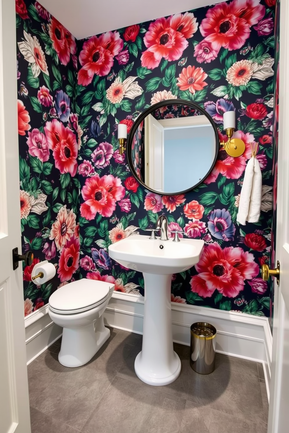 A striking guest bathroom featuring bold floral wallpaper that creates a vibrant focal point. The space includes a sleek white pedestal sink and a modern chrome faucet, complemented by a stylish round mirror with a black frame. The flooring consists of large gray tiles that contrast beautifully with the colorful wallpaper. Accents of gold in the light fixtures and towel racks add a touch of elegance to the overall design.