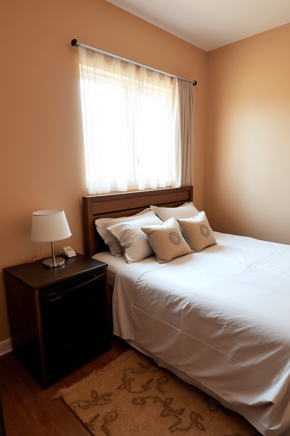 A cozy guest bedroom featuring a plush queen-sized bed with soft, neutral bedding and decorative throw pillows. A stylish mini fridge is discreetly placed next to a wooden nightstand, providing convenience for guests. The walls are painted in a warm beige tone, creating a welcoming atmosphere. A large window with sheer curtains allows natural light to flood the room, enhancing the inviting feel.