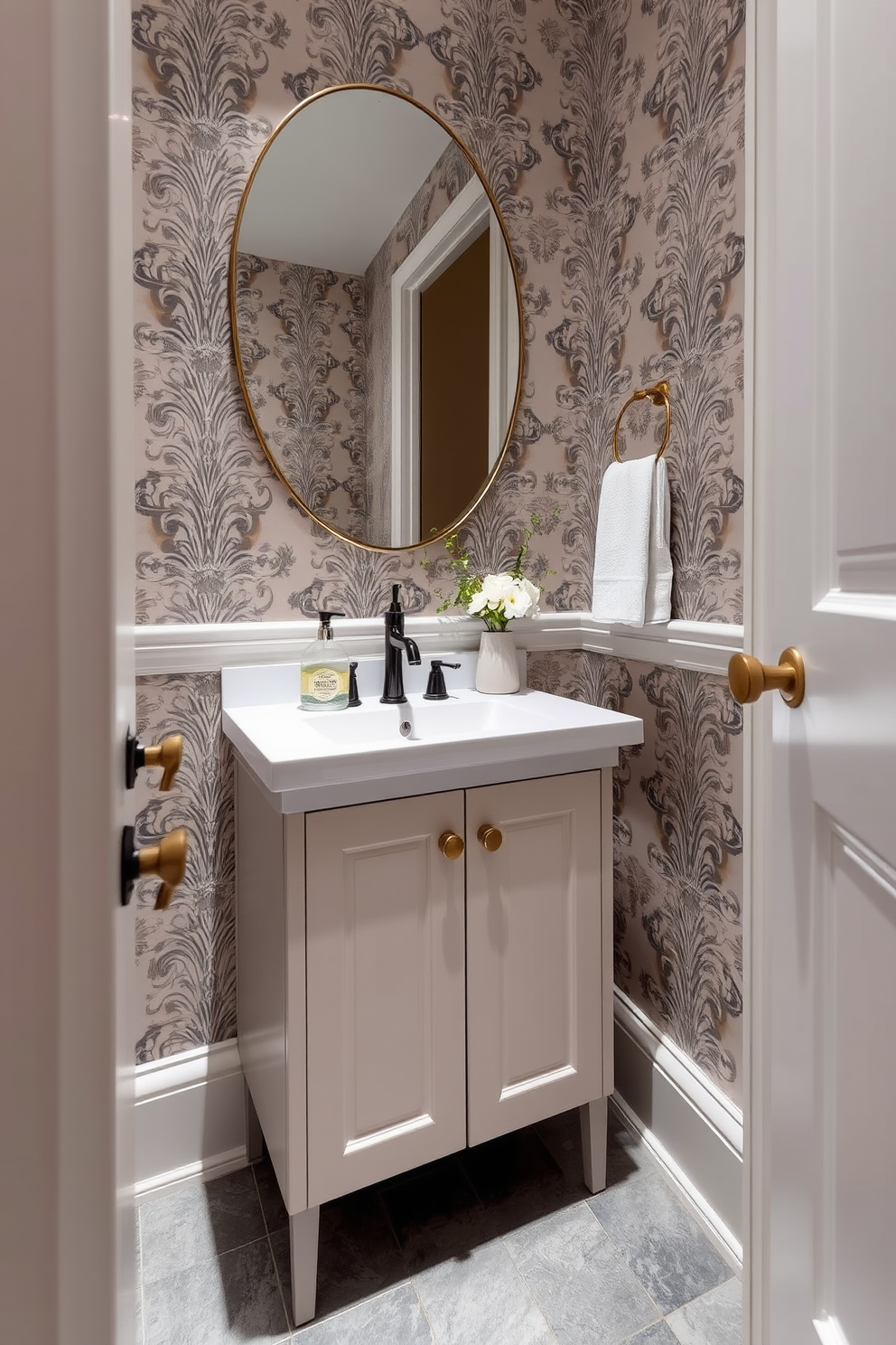 A sleek half bath features a glass soap dispenser that adds a modern touch to the space. The walls are adorned with elegant wallpaper in a soft neutral tone, and the flooring is a chic gray tile that complements the overall aesthetic.