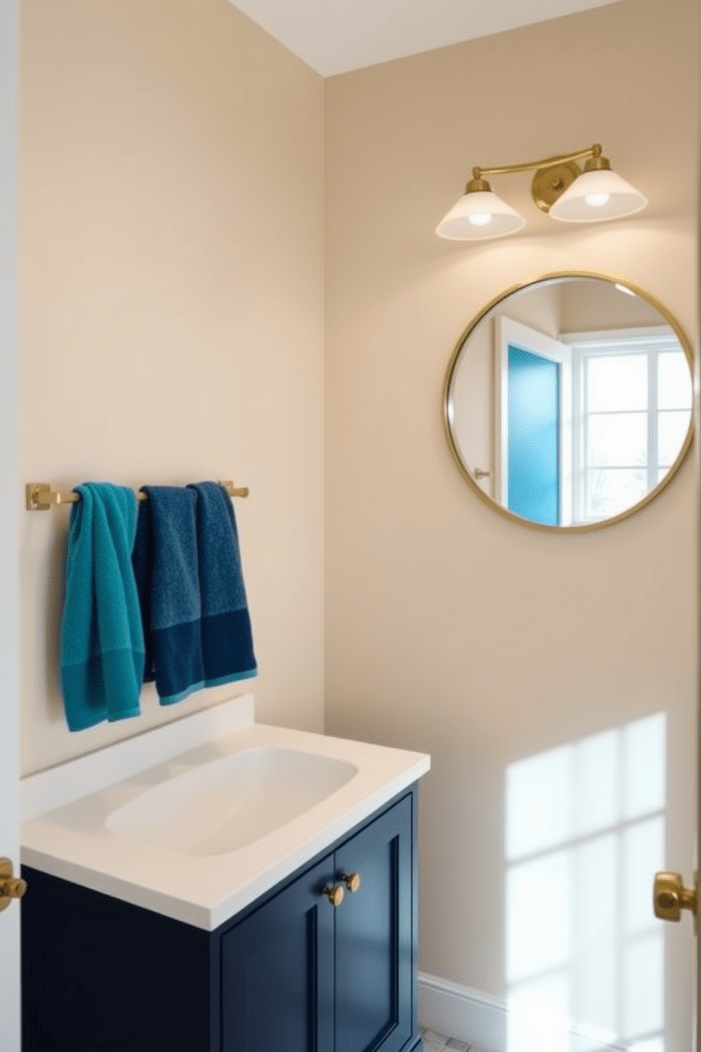 A serene hallway bathroom featuring neutral tones complemented by bold accent colors. The walls are painted in a soft beige, while vibrant teal accents are introduced through towels and decorative elements. The vanity showcases a sleek white countertop paired with a striking navy blue cabinet below. A large round mirror with a gold frame hangs above, reflecting the stylish light fixtures that illuminate the space.