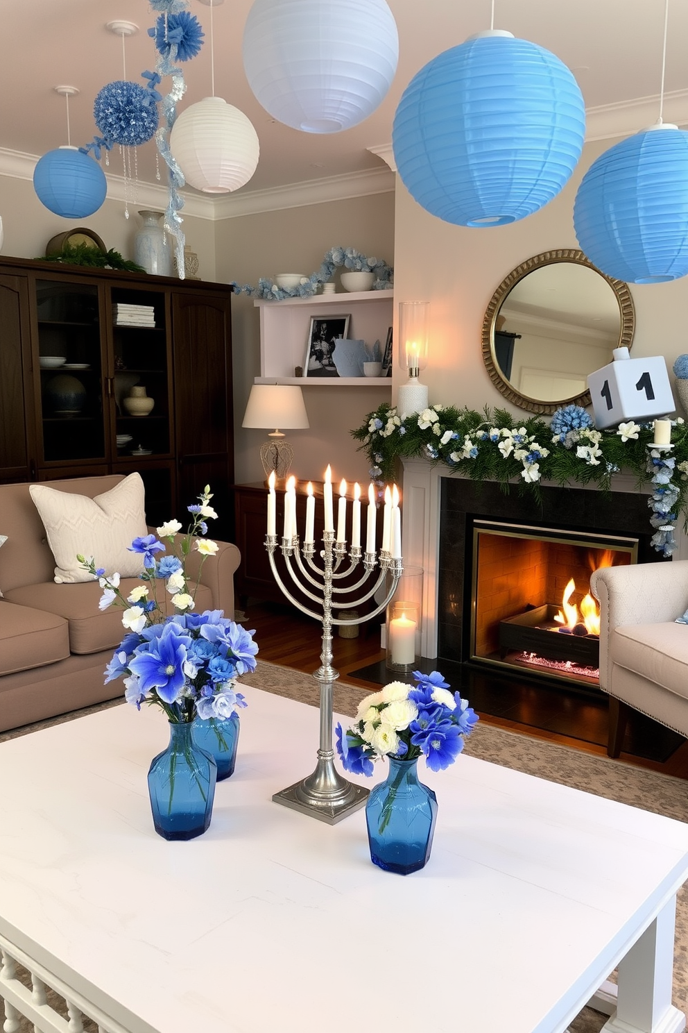 A cozy living room adorned for Hanukkah. The space features a beautiful menorah on the coffee table surrounded by fresh flowers in blue vases, creating a festive atmosphere. Soft blue and white decorations hang from the ceiling, while a large dreidel sits on the mantelpiece. The fireplace is lit, casting a warm glow over the room, enhancing the holiday spirit.