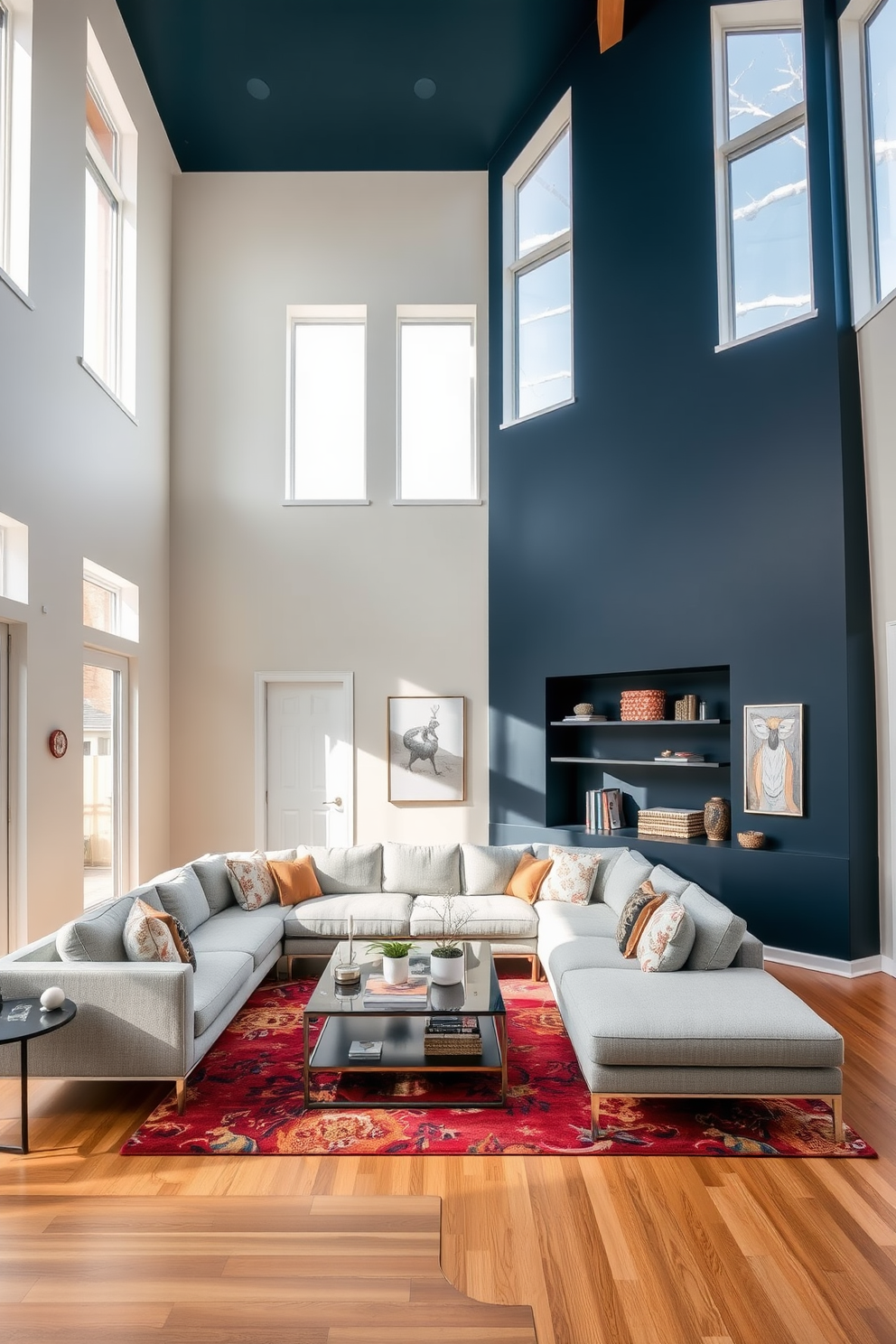 A spacious living room with a high ceiling that features large windows allowing natural light to flood the space. The focal point is a bold accent wall painted in deep navy blue, contrasting beautifully with the light neutral tones of the surrounding walls. A plush sectional sofa in a light gray fabric is arranged around a sleek coffee table made of glass and metal. Stylish artwork and decorative shelves adorn the accent wall, while a vibrant area rug adds warmth and texture to the hardwood floor.