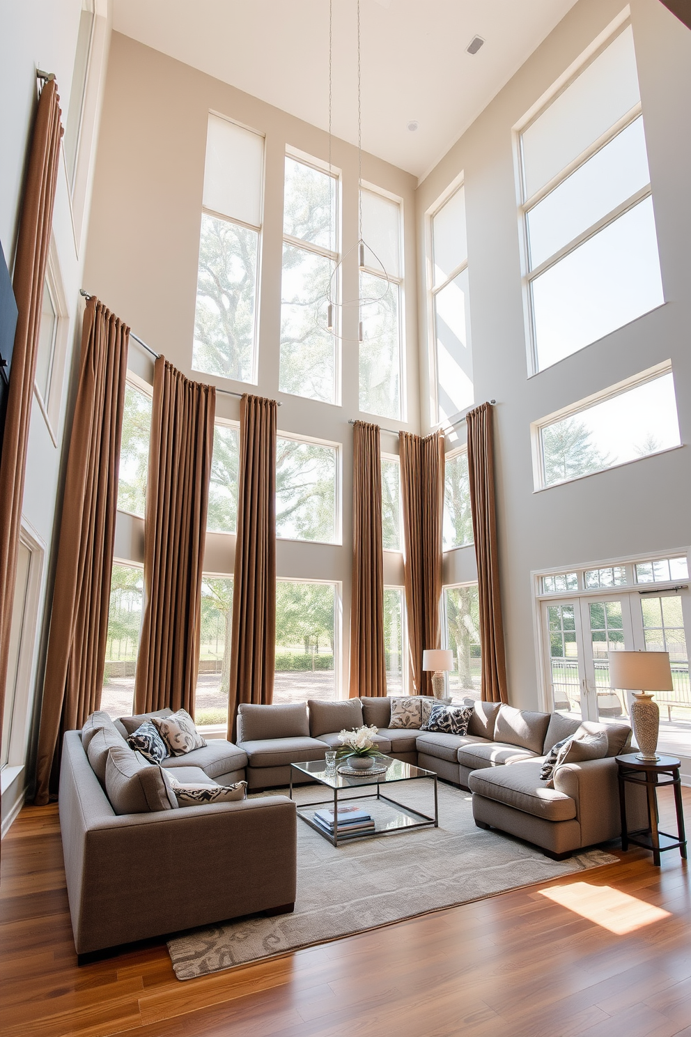 A high ceiling living room features expansive windows that allow natural light to flood the space. Tall drapes in a rich fabric frame the windows, enhancing the room's height and creating an elegant atmosphere. The walls are painted in a soft neutral tone, complementing the warm wood flooring. A large, plush sectional sofa is positioned around a stylish coffee table, inviting comfort and conversation.