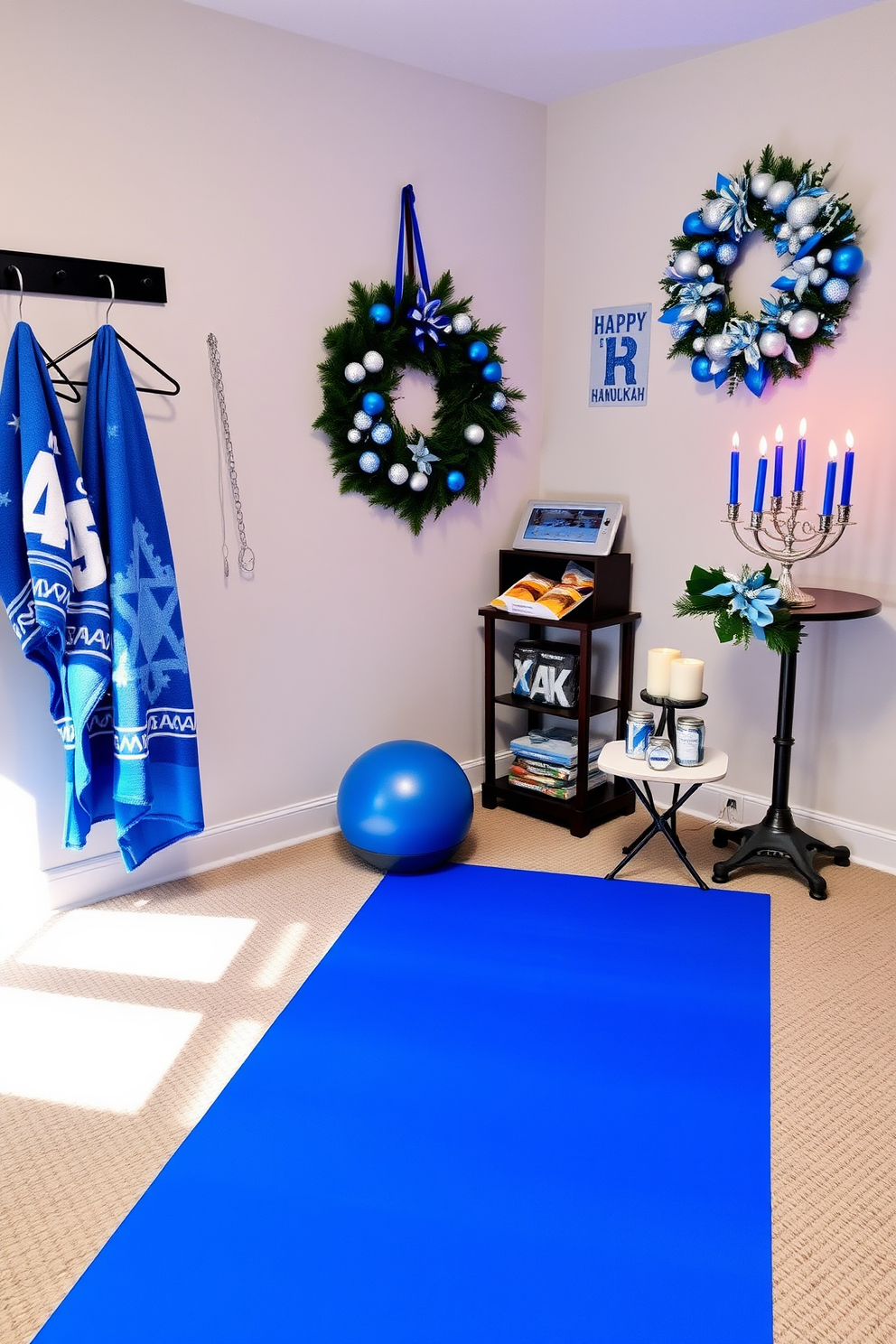 A cozy home gym setting adorned with festive Hanukkah decorations. The space features a large exercise mat in blue, complemented by holiday-themed towels hanging on a rack and a menorah placed on a nearby shelf. Brightly colored accents in silver and blue are incorporated throughout the room, including a decorative wreath on the wall. A small table holds healthy snacks and a festive candle arrangement to enhance the holiday spirit.