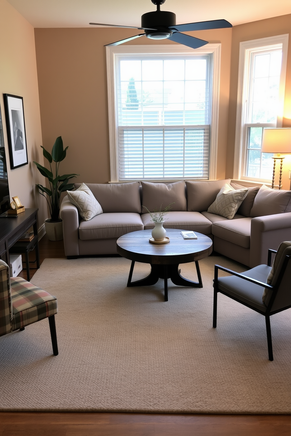 A cozy home office designed for casual meetings. The space features a plush sectional sofa in a soft gray fabric, paired with a round coffee table made of reclaimed wood. The walls are painted in a warm beige tone, creating an inviting atmosphere. A large area rug with a subtle geometric pattern adds texture and comfort underfoot.