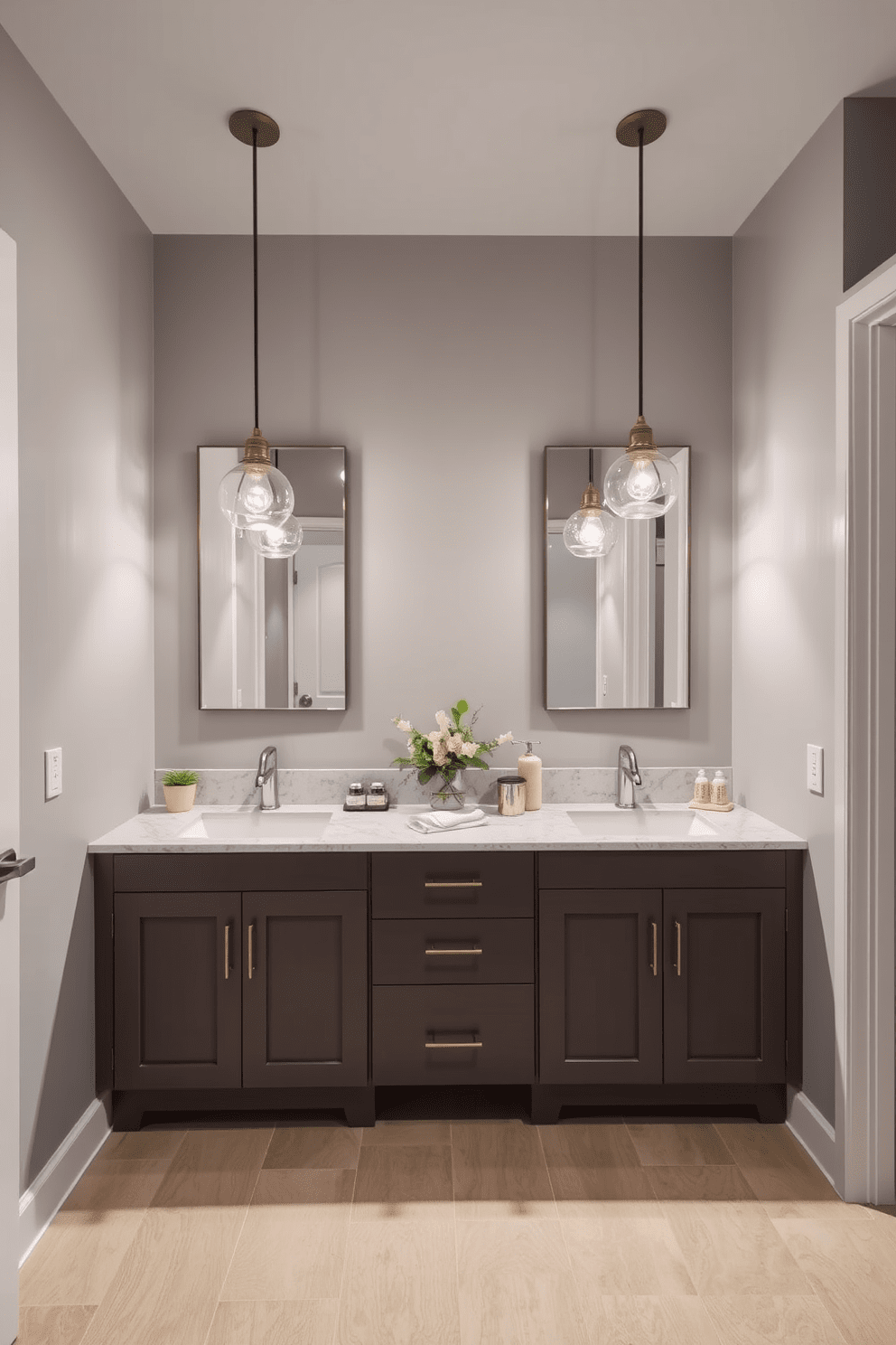 A stylish Jack and Jill bathroom featuring unique pendant lighting fixtures. The space is divided by a double vanity with elegant sinks and modern faucets, complemented by a sleek mirror above each sink. The walls are adorned with a soft gray hue, enhancing the contemporary feel of the room. Below, the floor is finished with large format tiles in a neutral tone, providing a clean and spacious appearance. Hanging above the vanities, the unique pendant lighting fixtures create a warm ambiance and serve as eye-catching design elements. Decorative plants are placed on the countertops, adding a touch of nature and freshness to the overall aesthetic.