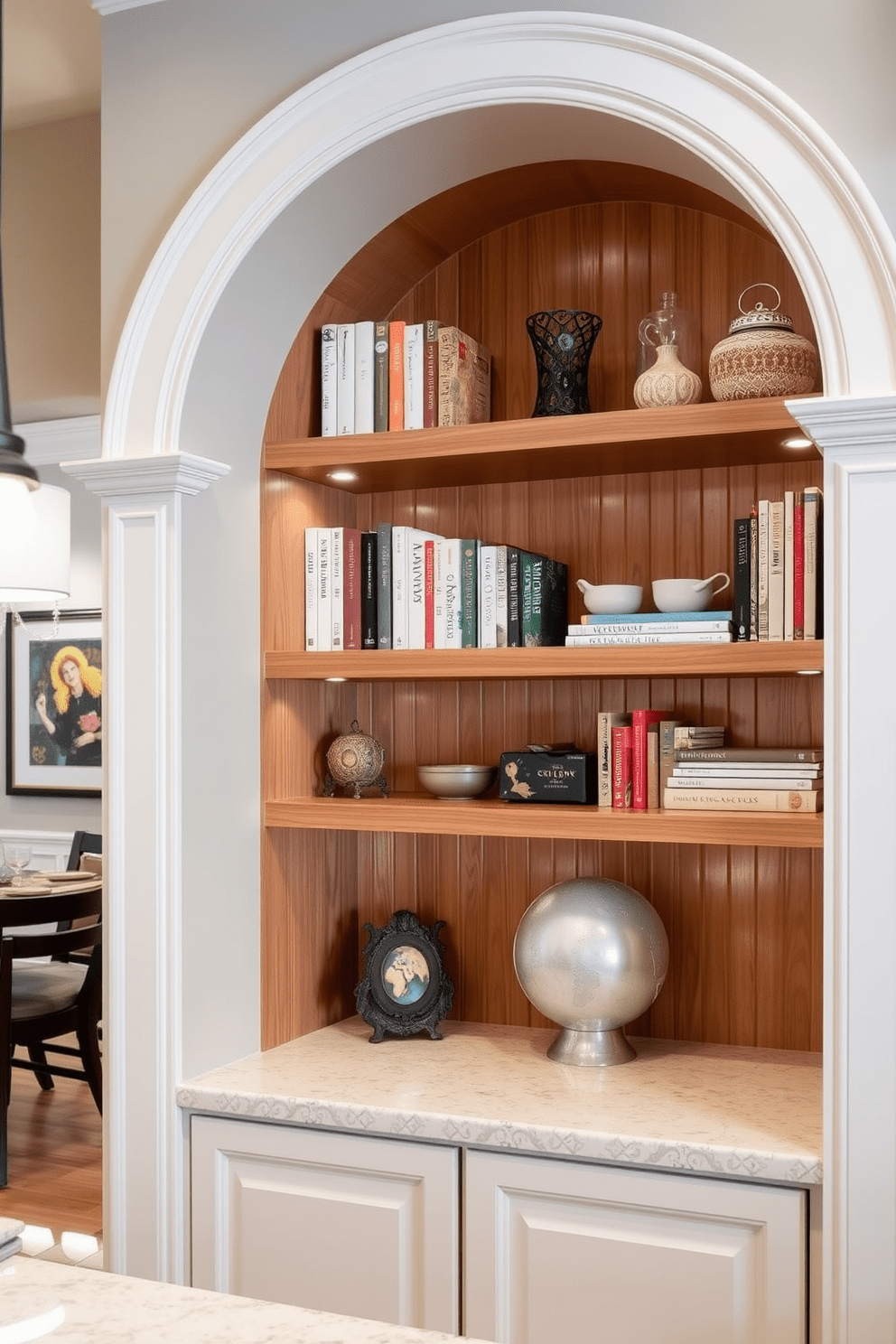 Arched alcove featuring built-in shelving that elegantly showcases a collection of cookbooks and decorative items. The shelving is framed by soft ambient lighting that highlights the natural wood finish and complements the surrounding kitchen decor. The kitchen arch design incorporates a seamless transition between the dining area and cooking space. It features a rounded top with decorative molding, enhancing the overall aesthetic while providing an inviting atmosphere for gatherings.