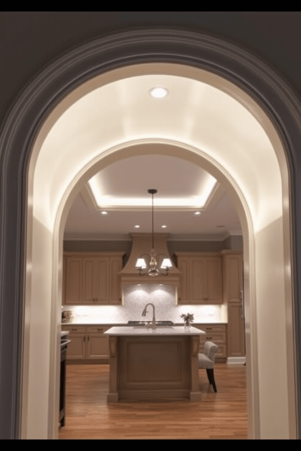 A stylish archway leads into the kitchen, featuring integrated LED lighting that highlights the elegant curves of the design. The arch is adorned with decorative molding, creating a seamless transition between the kitchen and the adjoining living space.