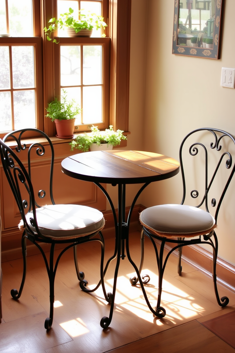 A charming bistro set is placed in a cozy kitchen nook. The round table features a rustic wooden top and elegant wrought iron legs, surrounded by two matching chairs with soft cushions. Natural light filters through a nearby window, highlighting the warm tones of the decor. Potted herbs sit on the windowsill, adding a touch of greenery to the inviting dining space.