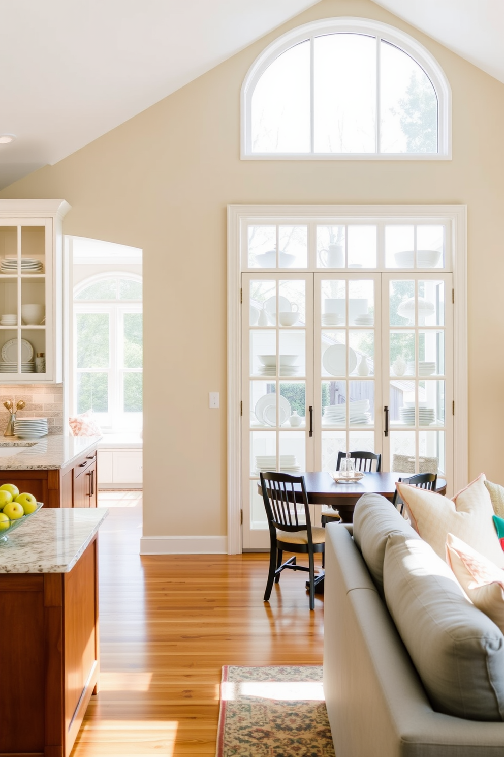 A bright and airy kitchen family room combo features large glass doors that elegantly showcase an array of colorful dishware. The open layout allows for seamless interaction between the kitchen and living space, creating a warm and inviting atmosphere for family gatherings.