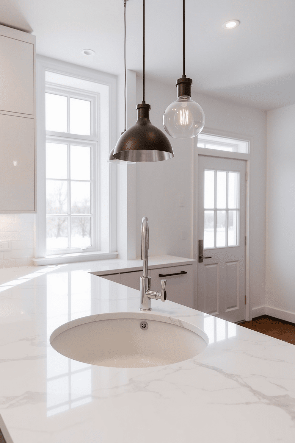 A modern kitchen featuring a round sink that serves as a focal point. The sink is surrounded by sleek, white cabinetry and a stunning marble countertop that enhances the overall elegance of the space. Above the sink, a large window allows natural light to flood in, illuminating the kitchen. Stylish pendant lights hang above, adding a warm ambiance to the room.