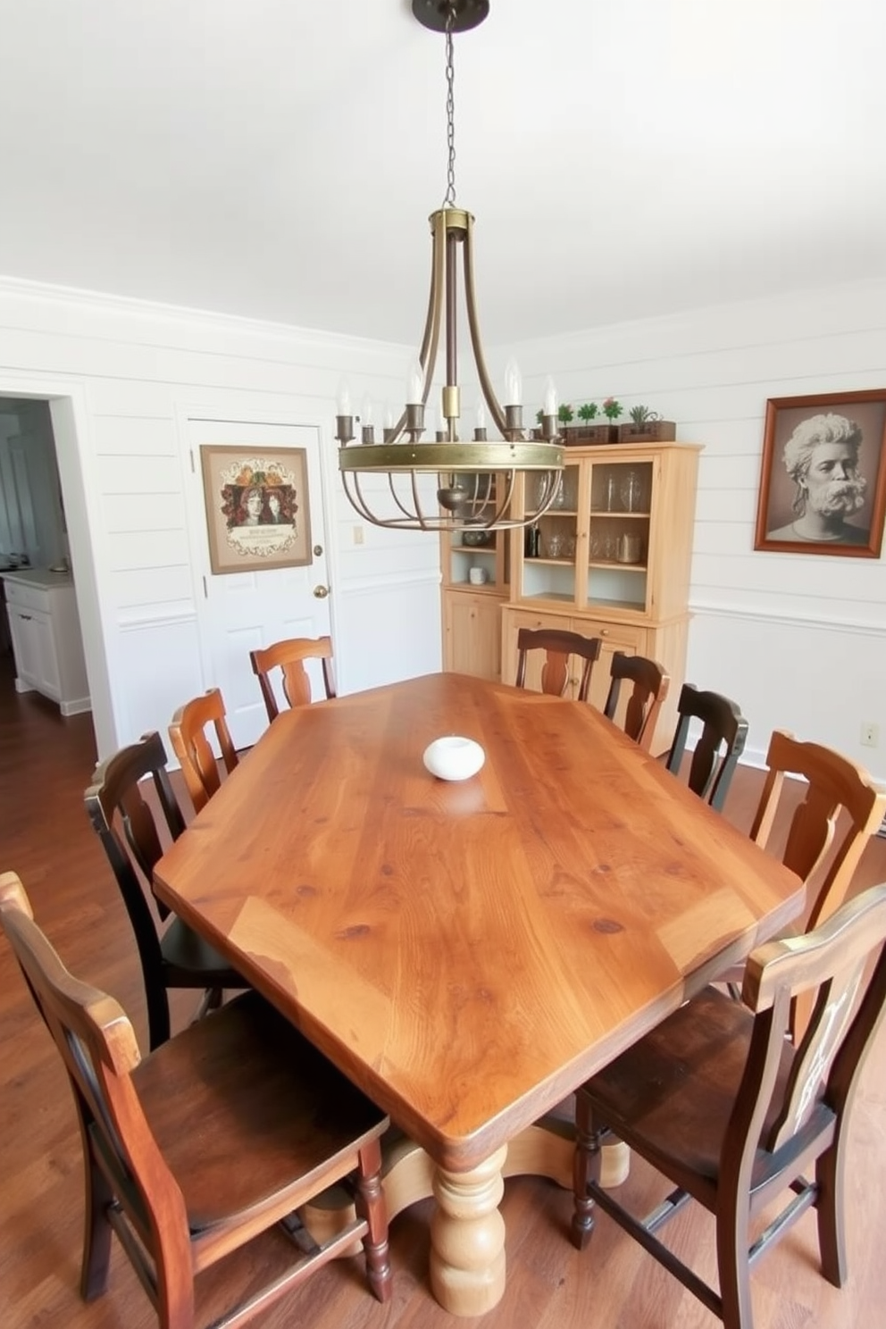 A rustic farmhouse table is the centerpiece of the L-shaped dining room, crafted from reclaimed wood with a natural finish that highlights its unique grain. Surrounding the table are mismatched wooden chairs, each with its own character, creating a warm and inviting atmosphere. The walls are adorned with shiplap paneling painted in a soft white, enhancing the rustic charm of the space. A large, vintage chandelier hangs above the table, providing a cozy glow during family meals and gatherings.