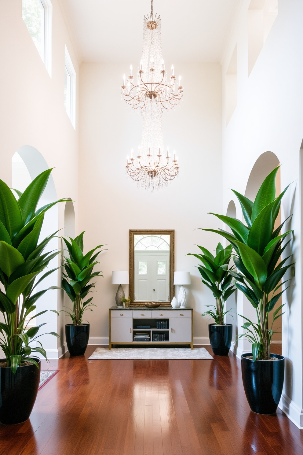 A grand entryway featuring large potted plants that add a touch of natural greenery. The space is illuminated by a stunning chandelier hanging from a high ceiling, creating an inviting atmosphere. The entryway boasts a sleek console table adorned with decorative items and a large mirror above it. Rich hardwood flooring complements the elegant design, while the walls are painted in a soft neutral tone to enhance the overall brightness.