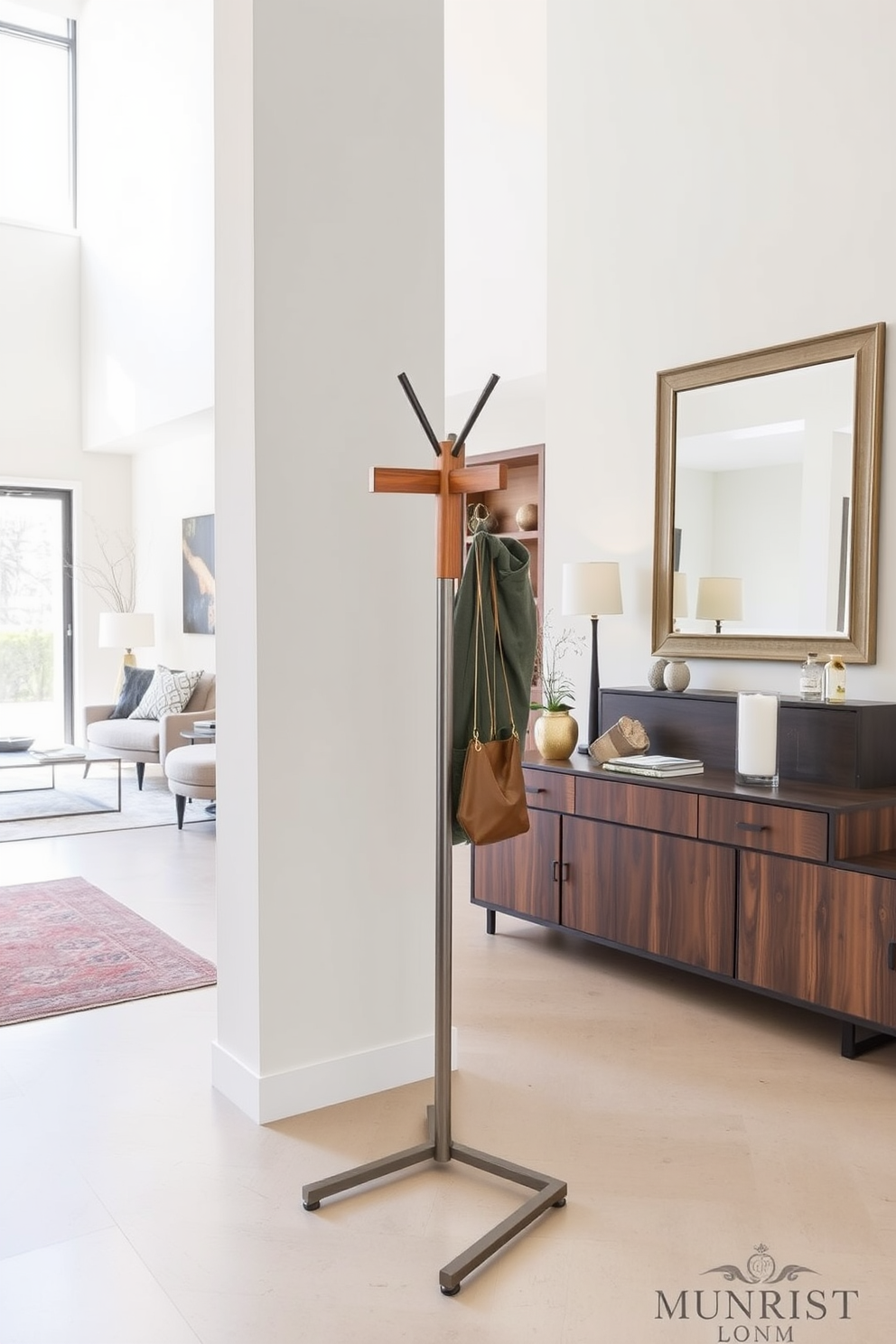 A sleek coat rack with a minimalist design stands prominently in the large entryway. It features a combination of wood and metal finishes, providing both style and functionality for hanging coats and accessories. The entryway is spacious and inviting, showcasing a blend of contemporary furniture and decorative elements. A large mirror hangs on one wall, reflecting natural light and enhancing the sense of openness in the space.