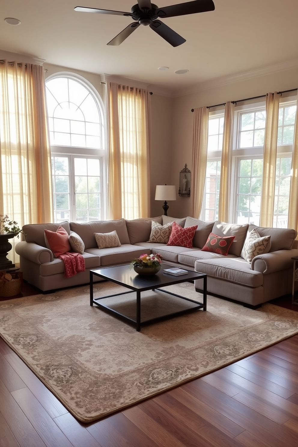 A large family room designed for comfort and warmth. Soft drapes frame the windows, allowing natural light to filter in while creating a cozy atmosphere. The room features a plush sectional sofa in a neutral tone, accented with colorful throw pillows. A large area rug anchors the seating area, providing a soft surface underfoot and enhancing the inviting ambiance.