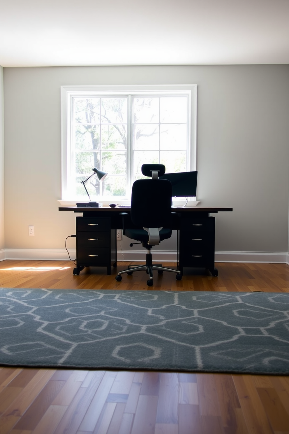 A spacious home office features a large wooden desk positioned in front of a window that allows natural light to flood the space. Behind the desk, a comfortable ergonomic chair complements the sleek design of the room. The walls are painted in a calming light gray, creating a serene backdrop for productivity. A stylish rug in a geometric pattern defines the area, adding warmth and texture to the hardwood floor.