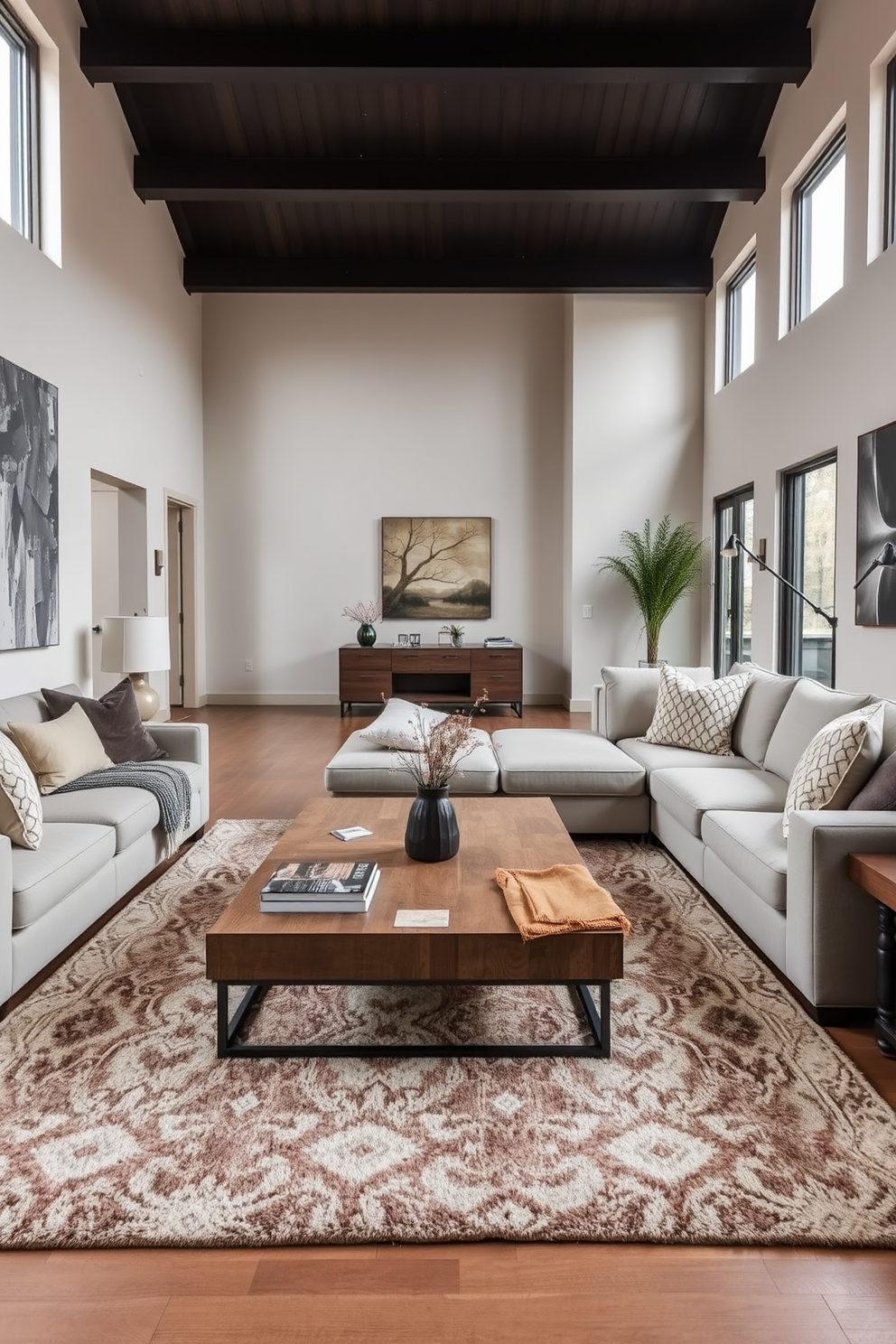 A large coffee table serves as the focal point of the living room, surrounded by plush sectional sofas in a neutral color palette. The space features a cozy area rug underneath, accentuating the warmth of the room and inviting conversation. The walls are adorned with tasteful artwork that complements the overall design, while large windows allow natural light to flood the space. Decorative cushions in varying textures and patterns add depth and interest to the seating arrangement.