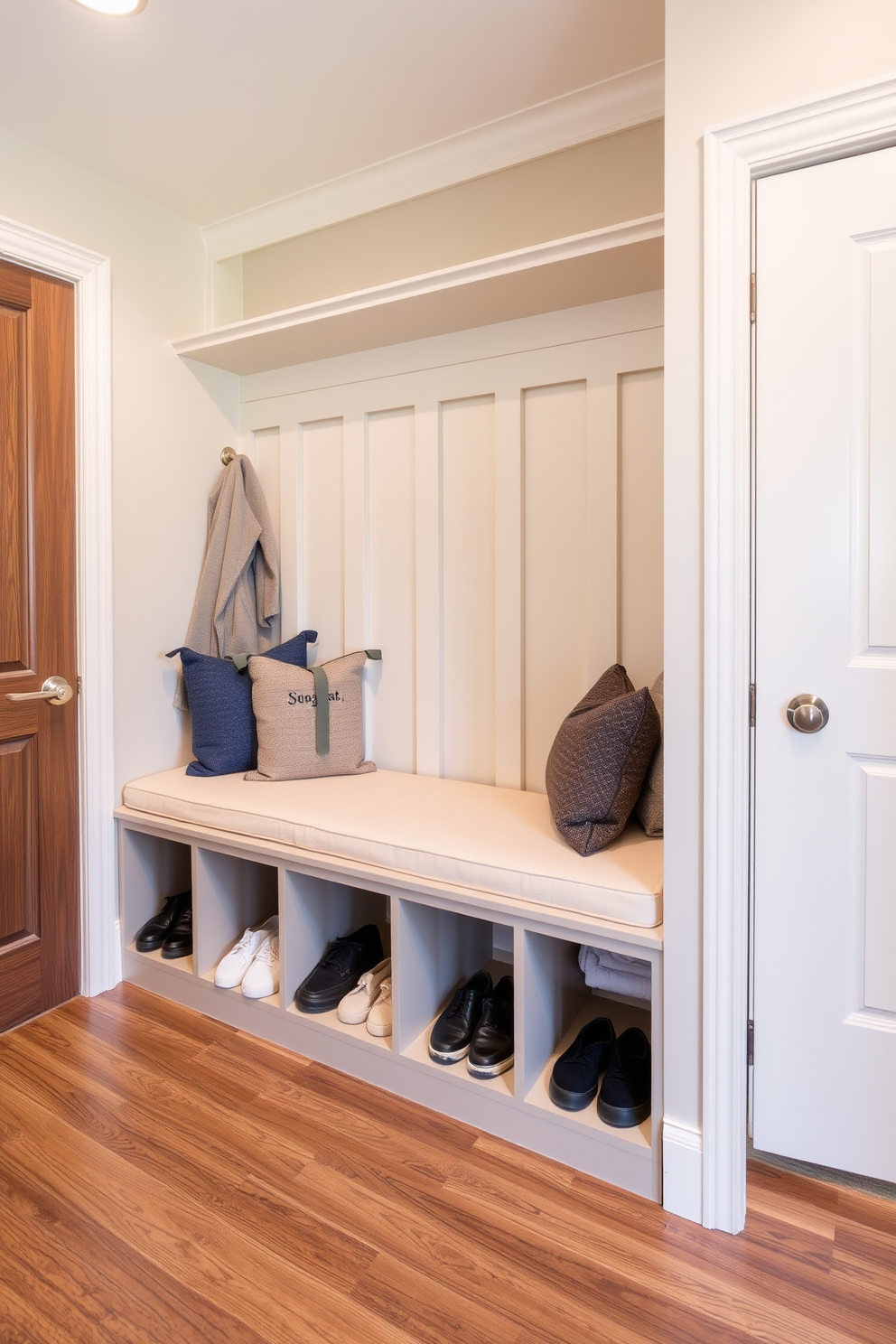 A spacious mudroom features a built-in bench with soft cushions, providing a comfortable spot to sit while putting on shoes. Below the bench, there are organized shoe cubbies, neatly storing footwear and keeping the area tidy.