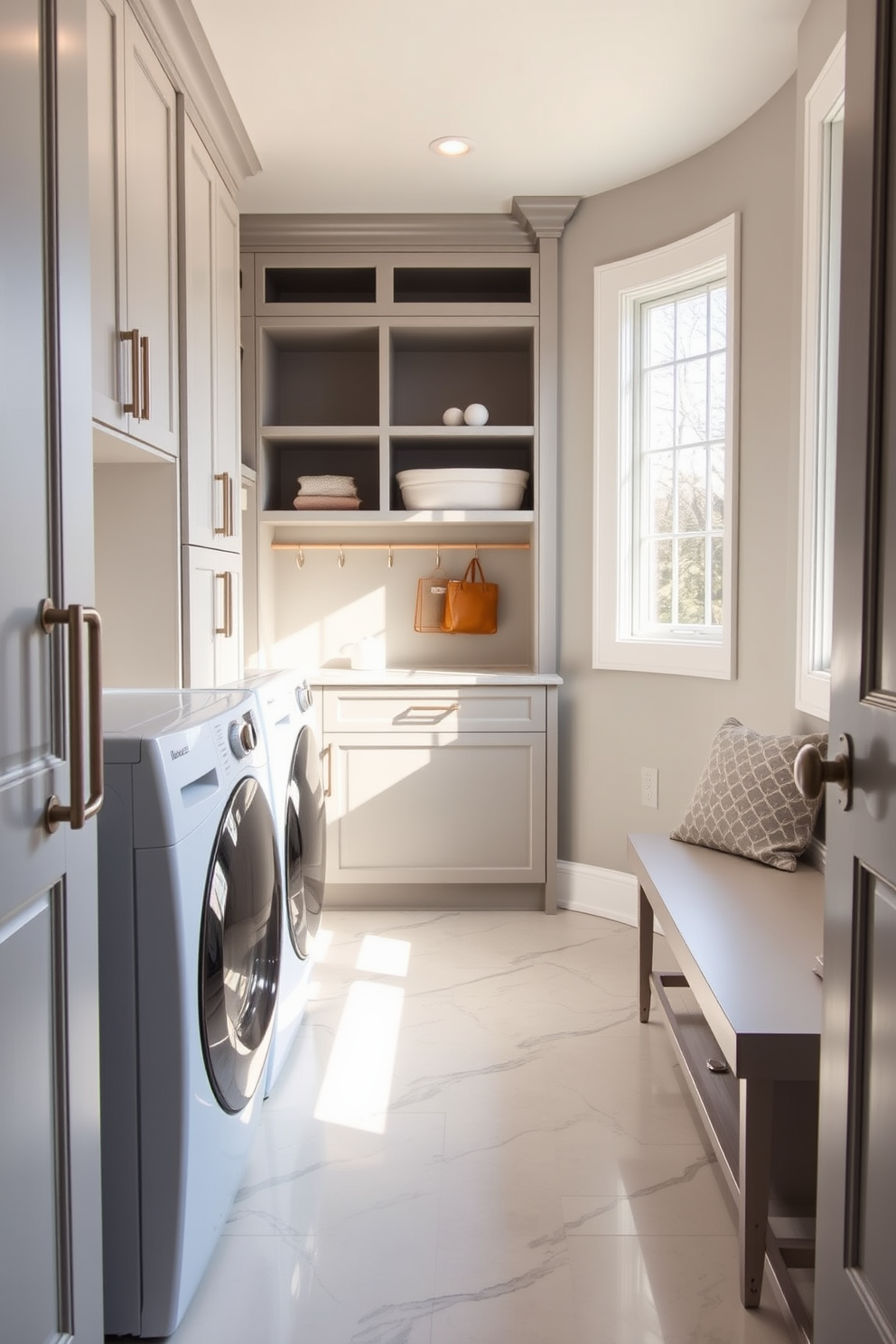 A modern laundry mudroom features sleek appliances seamlessly integrated behind cabinetry doors, creating a clean and uncluttered look. The space is designed with ample storage, including shelves and hooks for organization, and a stylish bench for convenience. Natural light floods the room through a large window, highlighting the elegant tile flooring that complements the overall aesthetic. A subtle color palette of soft grays and whites enhances the serene atmosphere, making laundry day feel less like a chore.