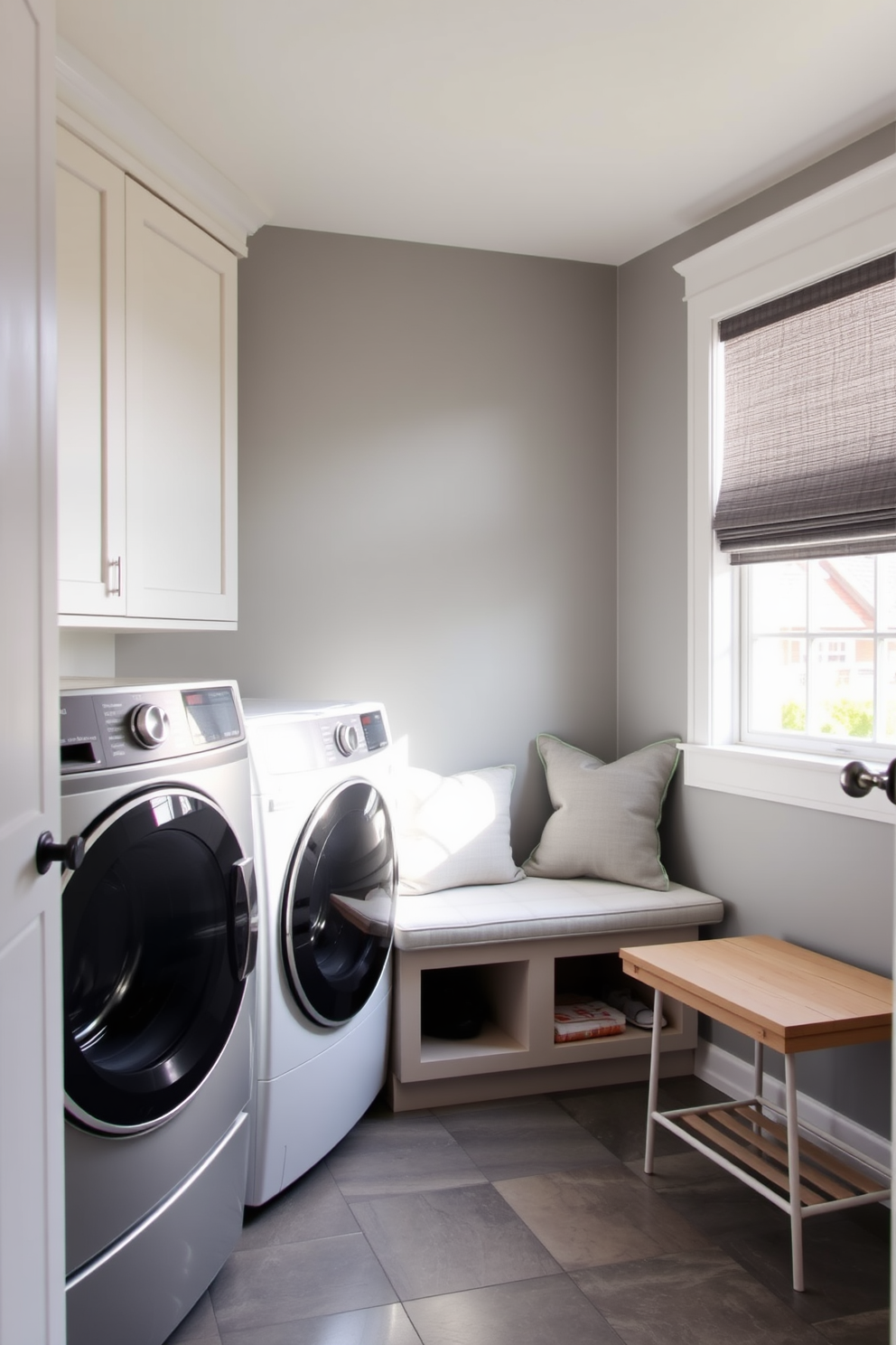 A modern laundry mudroom featuring smart technology for energy efficiency. The space includes a sleek washer and dryer with energy-saving features, surrounded by built-in cabinetry for storage. Natural light floods the room through a large window, illuminating a stylish bench with storage underneath. The walls are painted in a soft gray, and the floor is covered with durable, water-resistant tiles.