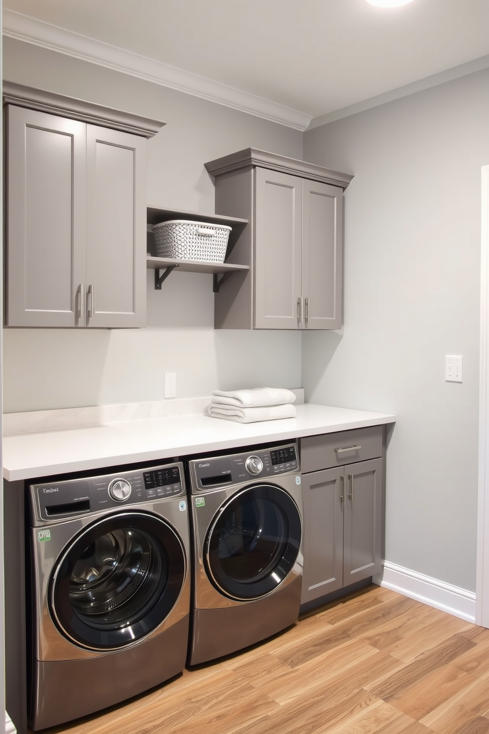 A functional folding station is designed with a spacious countertop for easy laundry organization. Below the countertop, ample storage cabinets keep laundry essentials neatly tucked away. The walls are painted in a soft grey hue, creating a calm atmosphere. Durable vinyl flooring in a wood-like finish adds warmth and practicality to the space.