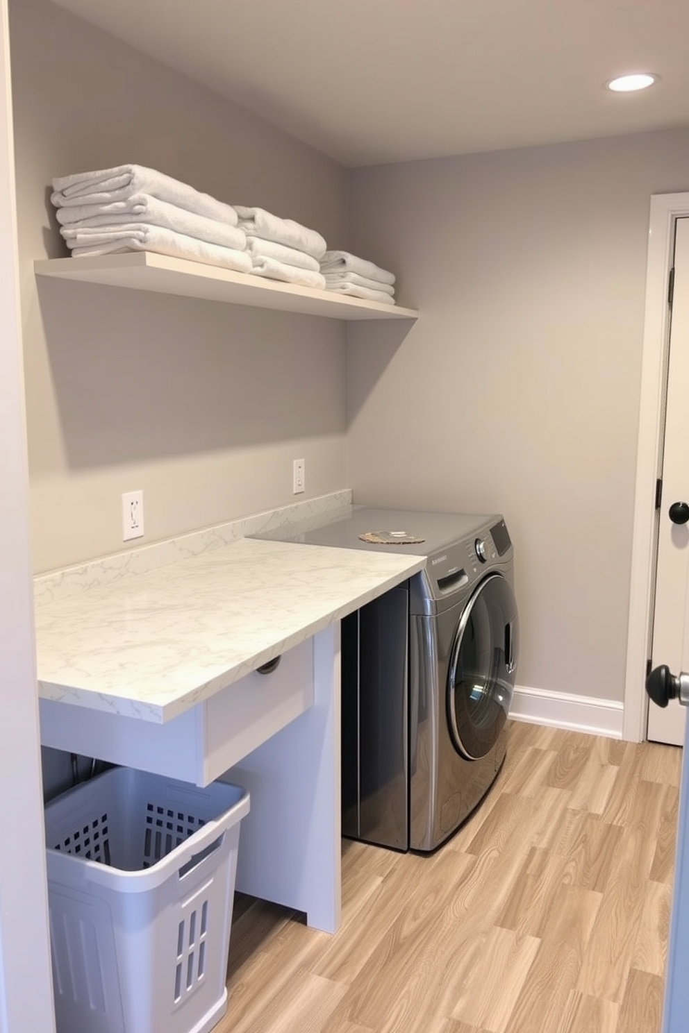 A functional laundry room in the basement featuring a spacious countertop for sorting clothes. The countertop is made of durable quartz with a subtle pattern, complemented by a built-in laundry basket underneath for easy access. The walls are painted in a soft gray to create a calming atmosphere, while the floor is covered with water-resistant vinyl planks for practicality. Shelving above the countertop holds neatly folded towels and laundry supplies, enhancing organization and convenience.