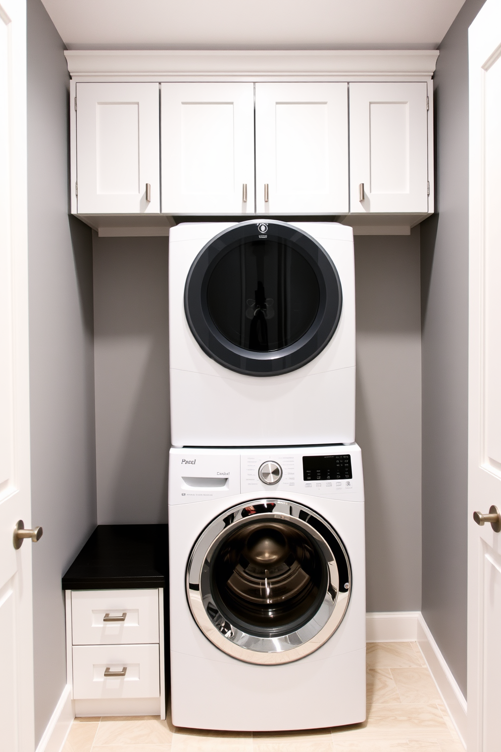 A modern laundry room featuring a stacked washer and dryer positioned neatly between sleek overhead cabinets. The cabinets are finished in a crisp white, providing a clean and bright aesthetic, while the walls are painted in a soft gray tone for a calming effect.